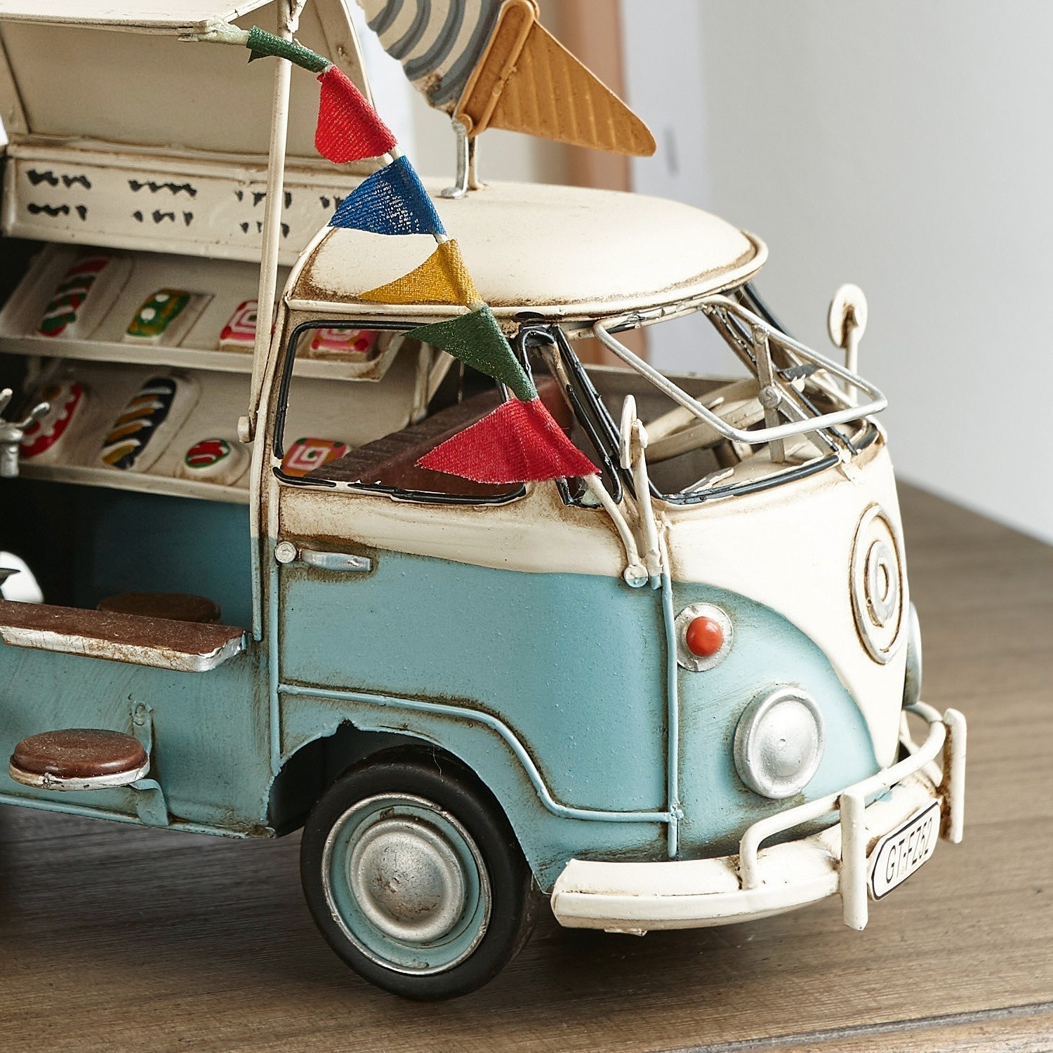 Blau-weißer Metallmodell-Transporter mit bunten Wimpeln und Retro-Details auf Holztisch