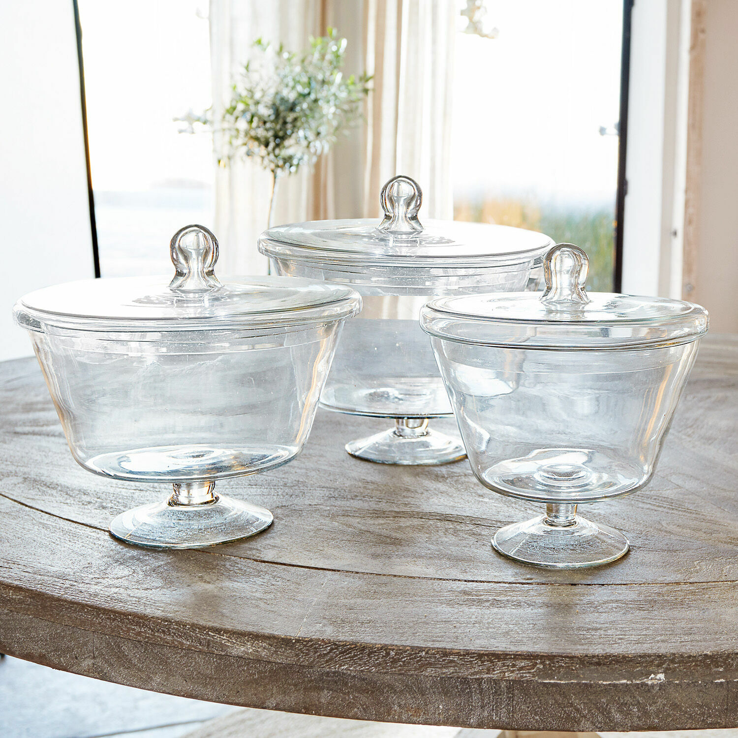 Set aus drei transparenten Glasbehältern mit Deckeln auf einem Holztisch