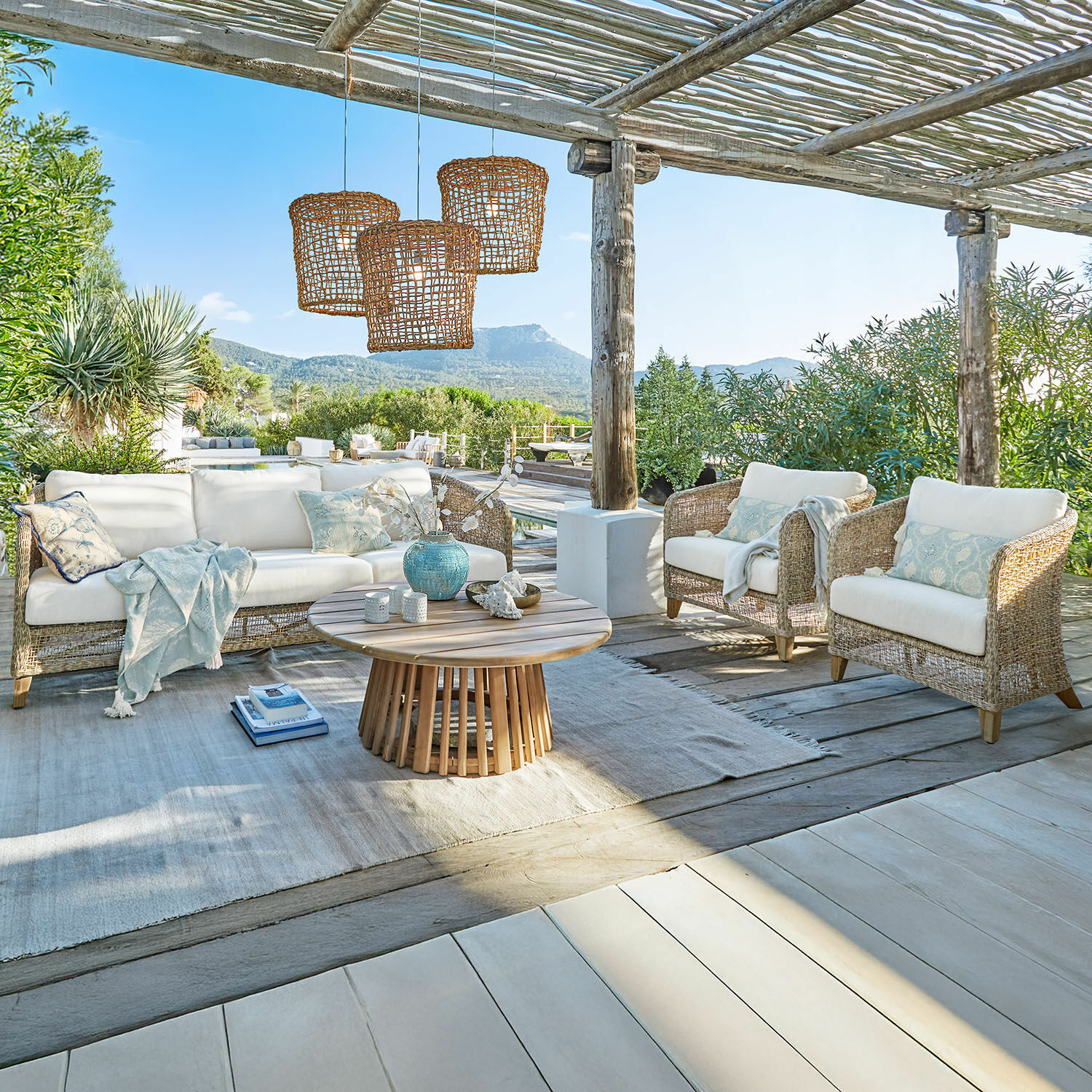 Gartenmöbel-Set aus natürlichem Rattan mit weißen Polstern und hellem Holztisch auf Terrasse