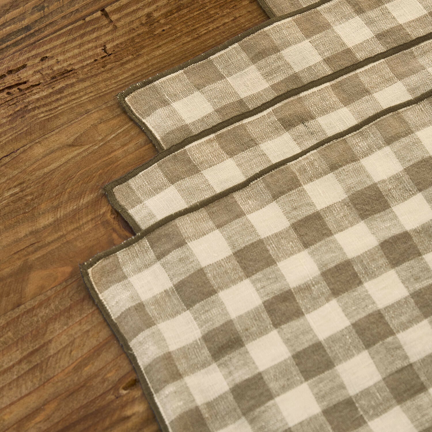 Leinenservietten mit kariertem Muster in Beige und Creme auf Holztisch, Tischdekoration