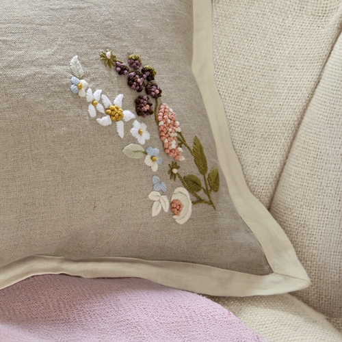 Beiges Leinenkissen mit bunter Blumenstickerei und cremefarbenem Rand als Dekokissen