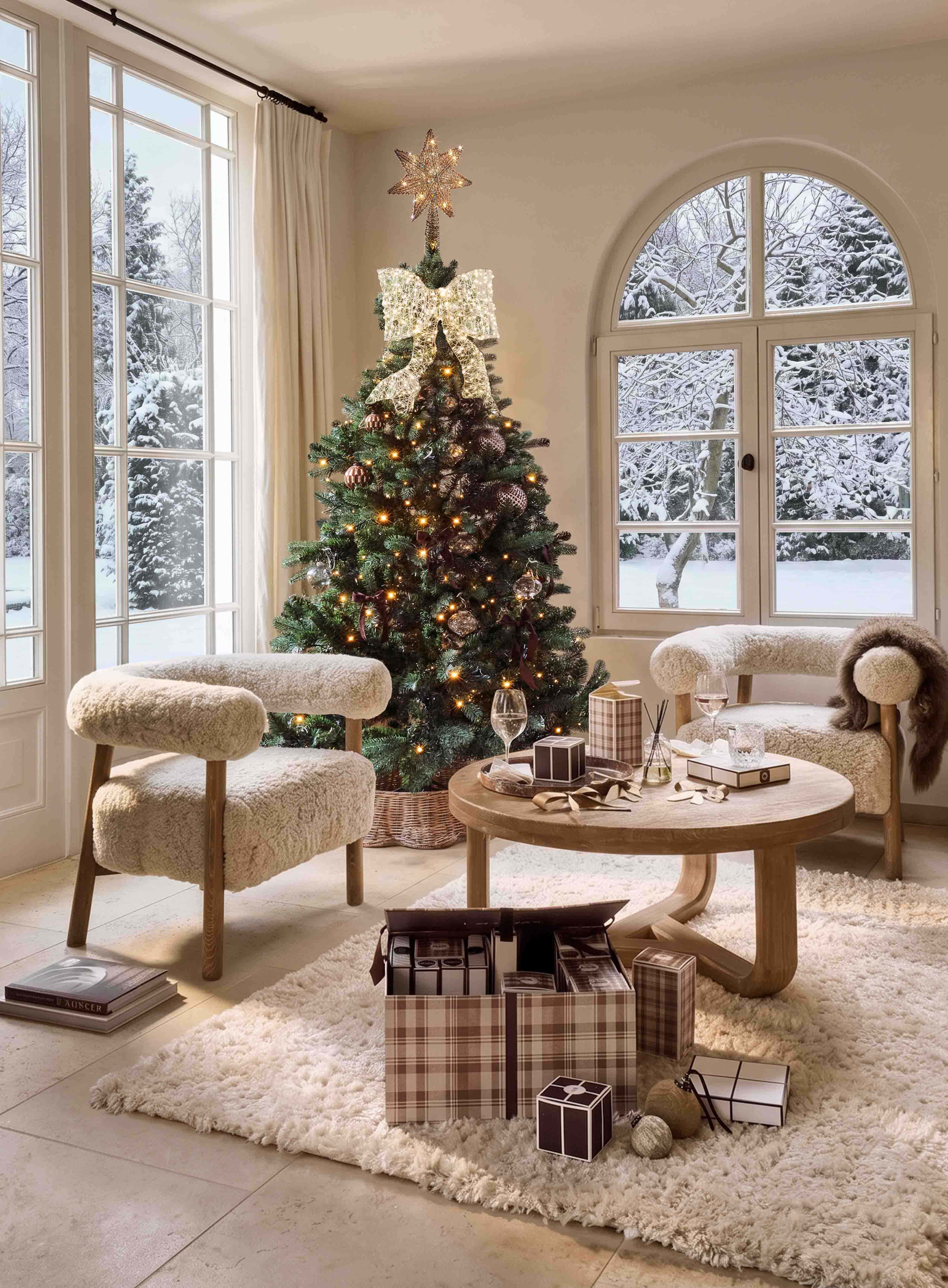 Weihnachtsbaum mit leuchtendem Stern und großer Schleife in gemütlichem Wohnzimmer mit Blick auf verschneiten Garten