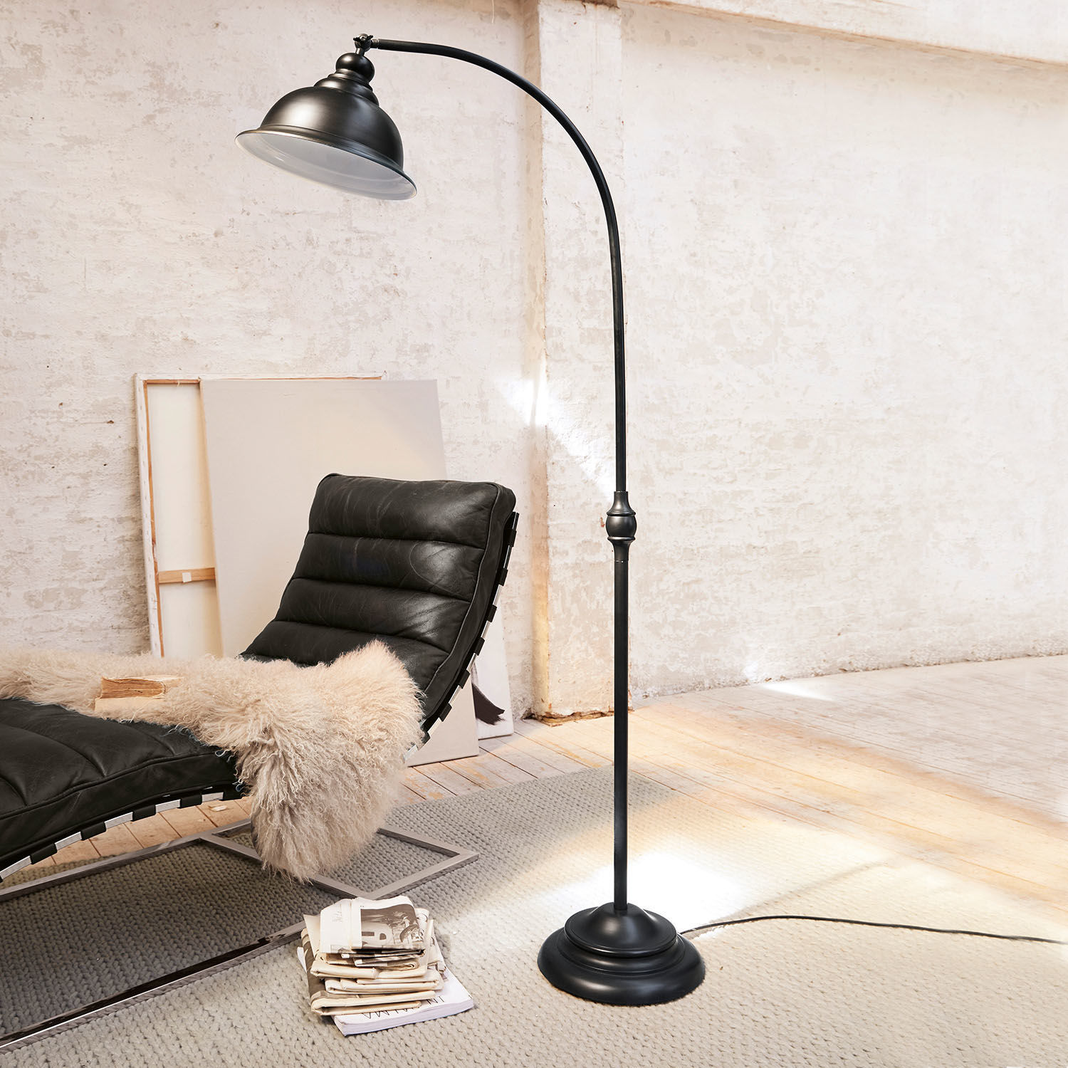 Schwarze Metall-Stehlampe mit gebogenem Arm in modernem Raum mit Sessel und Teppich
