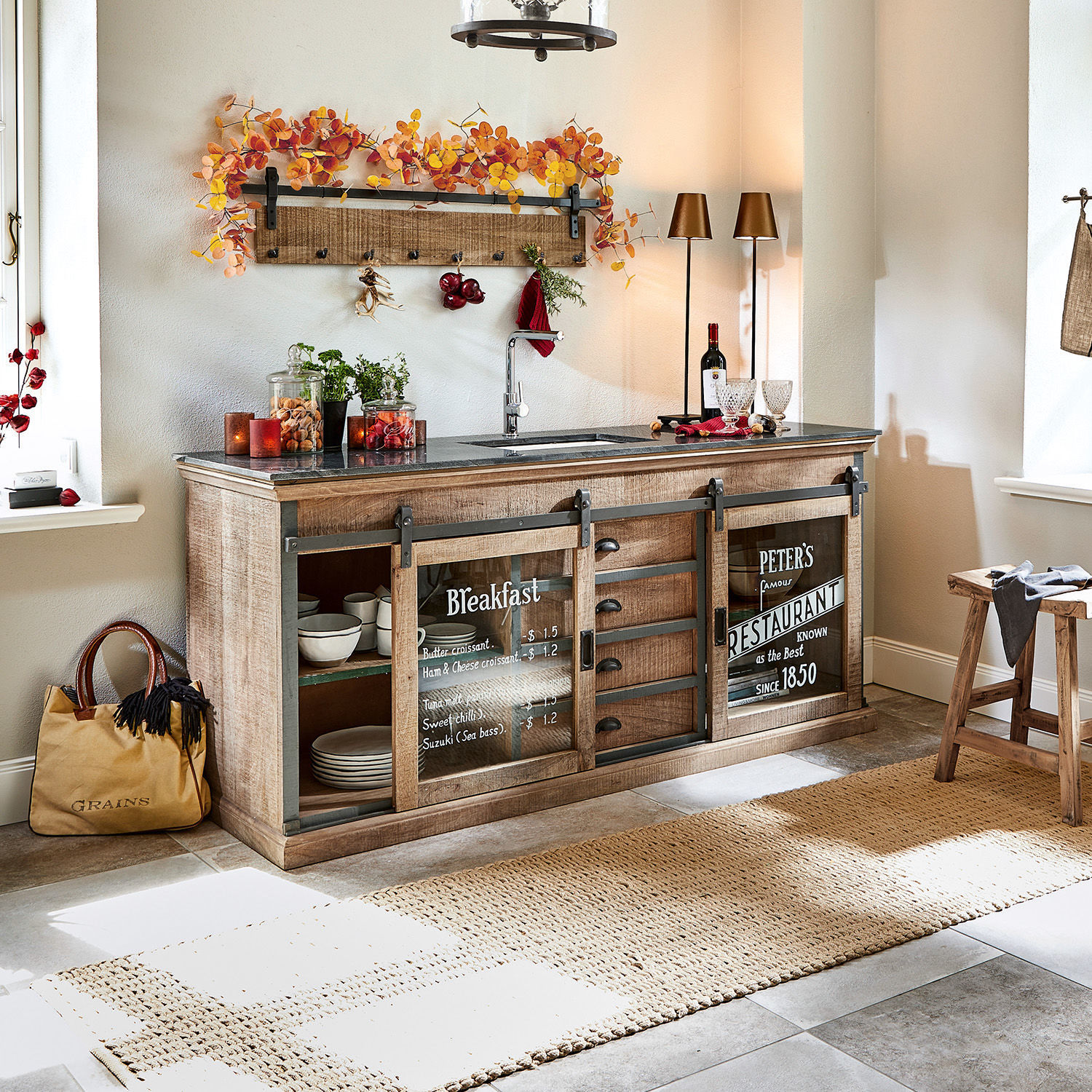 Küche mit hellem Holzschrank, schwarzer Arbeitsplatte und Glastüren mit Frühstücksmenü-Aufdruck