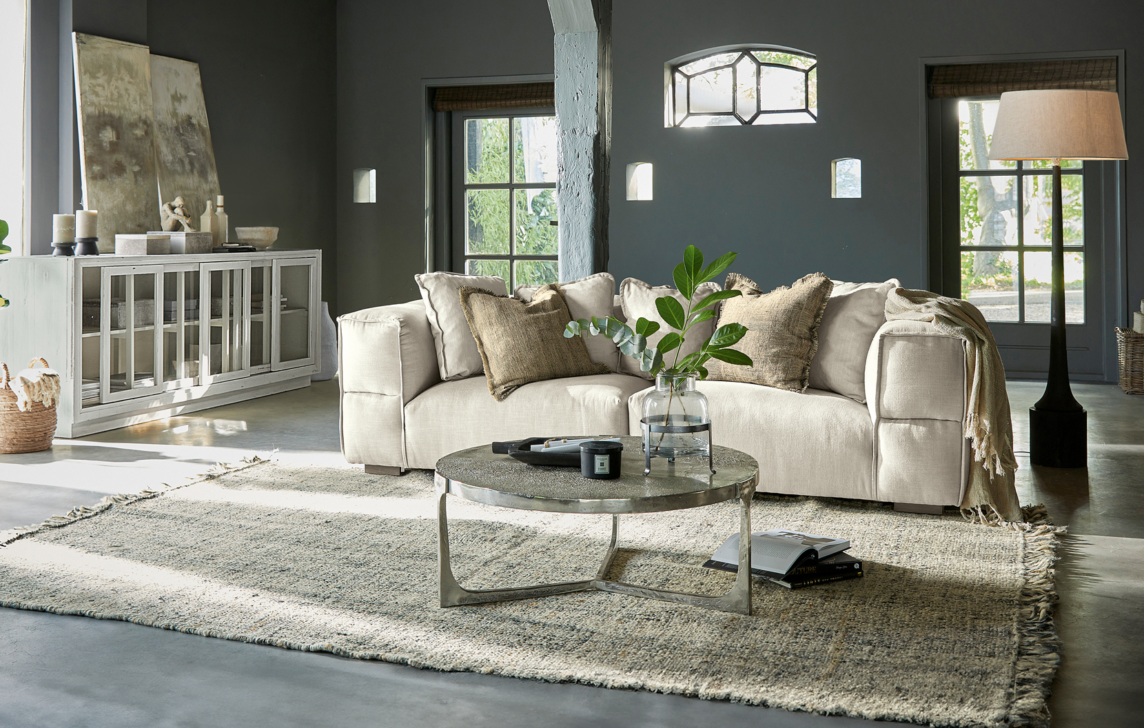 Geräumiges Wohnzimmer mit beigem Stoffsofa, Metall-Couchtisch und Teppich im Industrial-Stil
