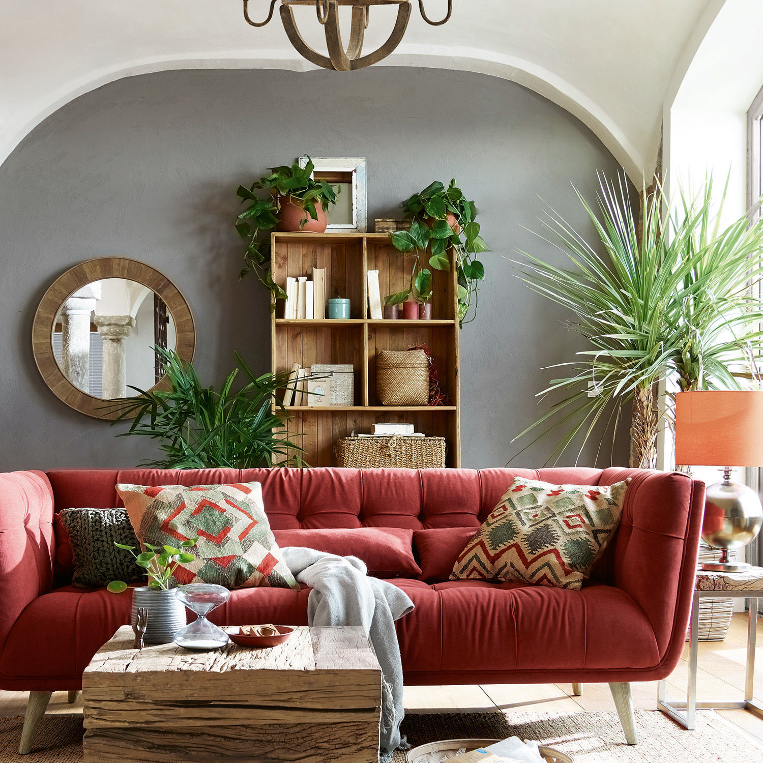 Rotes Samtsofa mit geometrischen Kissen in modernem Wohnzimmer mit rustikalem Holztisch