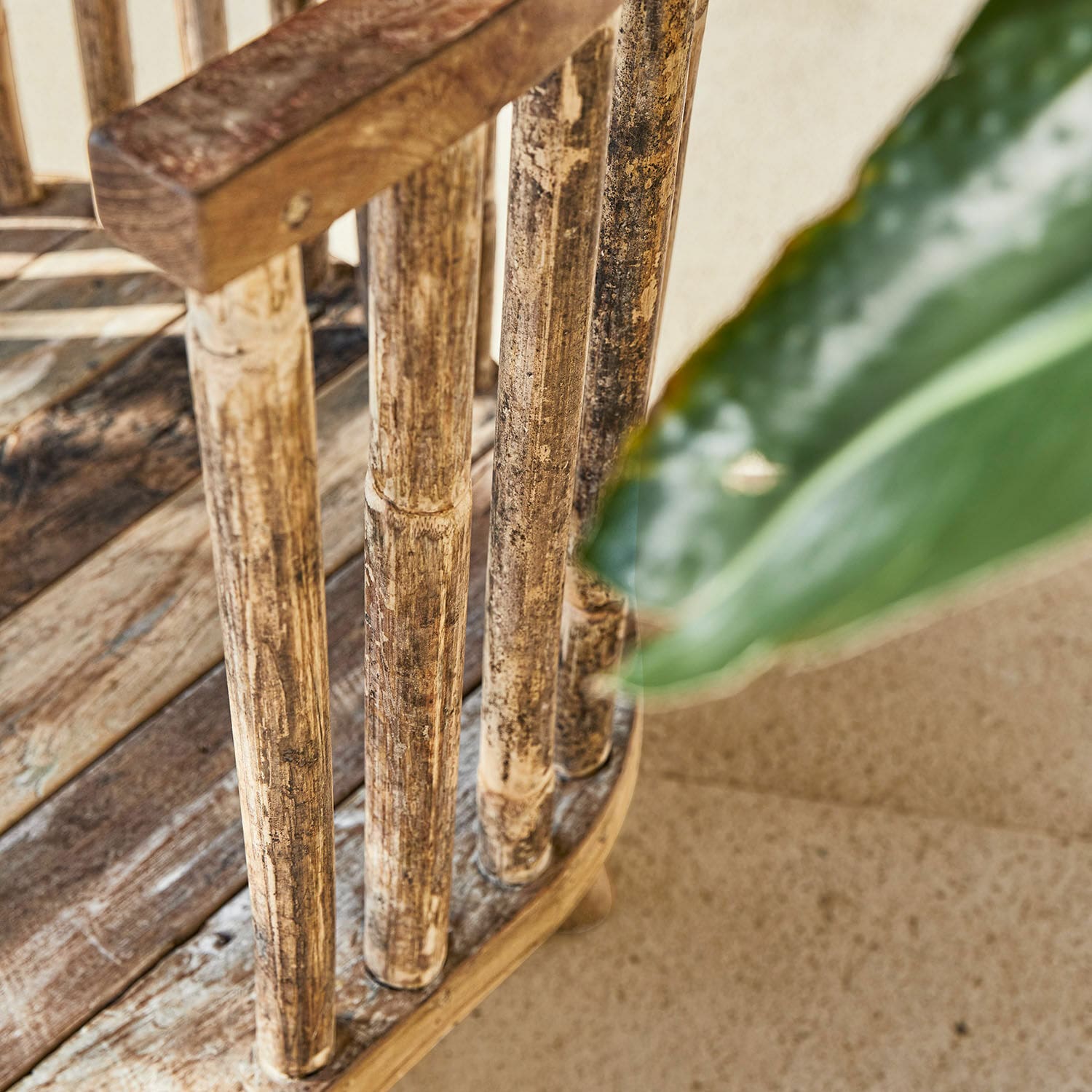 Nahaufnahme eines natürlichen, gealterten Holzstuhlrückens mit sichtbarer Holzstruktur und unscharfem Blatt.
