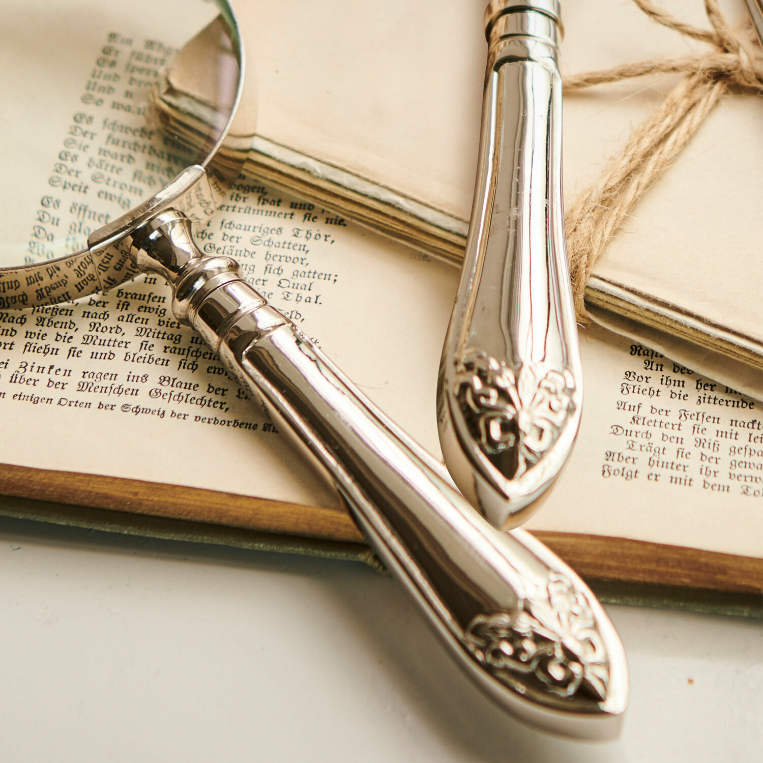 Silberne Metall-Lupe mit verziertem Griff auf alten Büchern und Dokumenten, Lesehilfe Accessoire