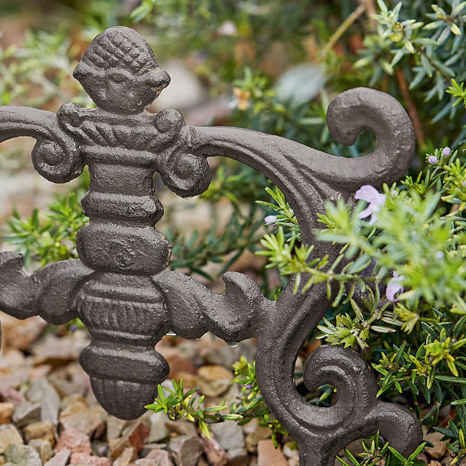 Dekoratives Gartenelement aus dunkelgrauem Schmiedeeisen vor Pflanzenhintergrund