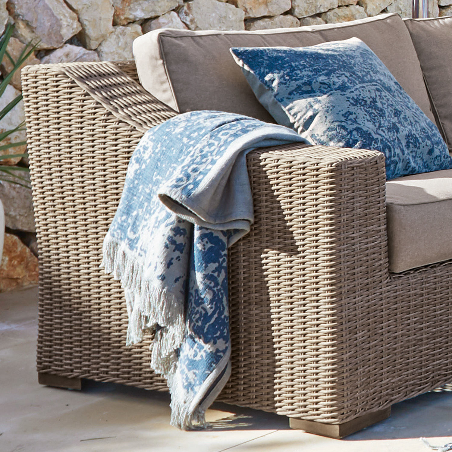 Beiger Polyrattan-Sessel mit blauem Dekokissen und Decke, Outdoor-Möbel für Terrasse