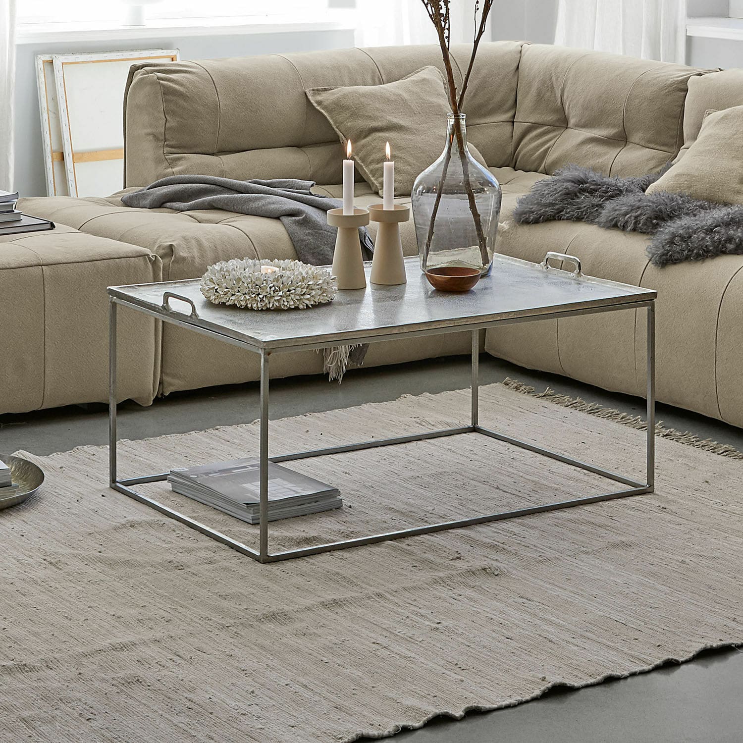 Moderner Couchtisch mit Metallrahmen und silberner Tischplatte auf beigem Teppich im Wohnzimmer