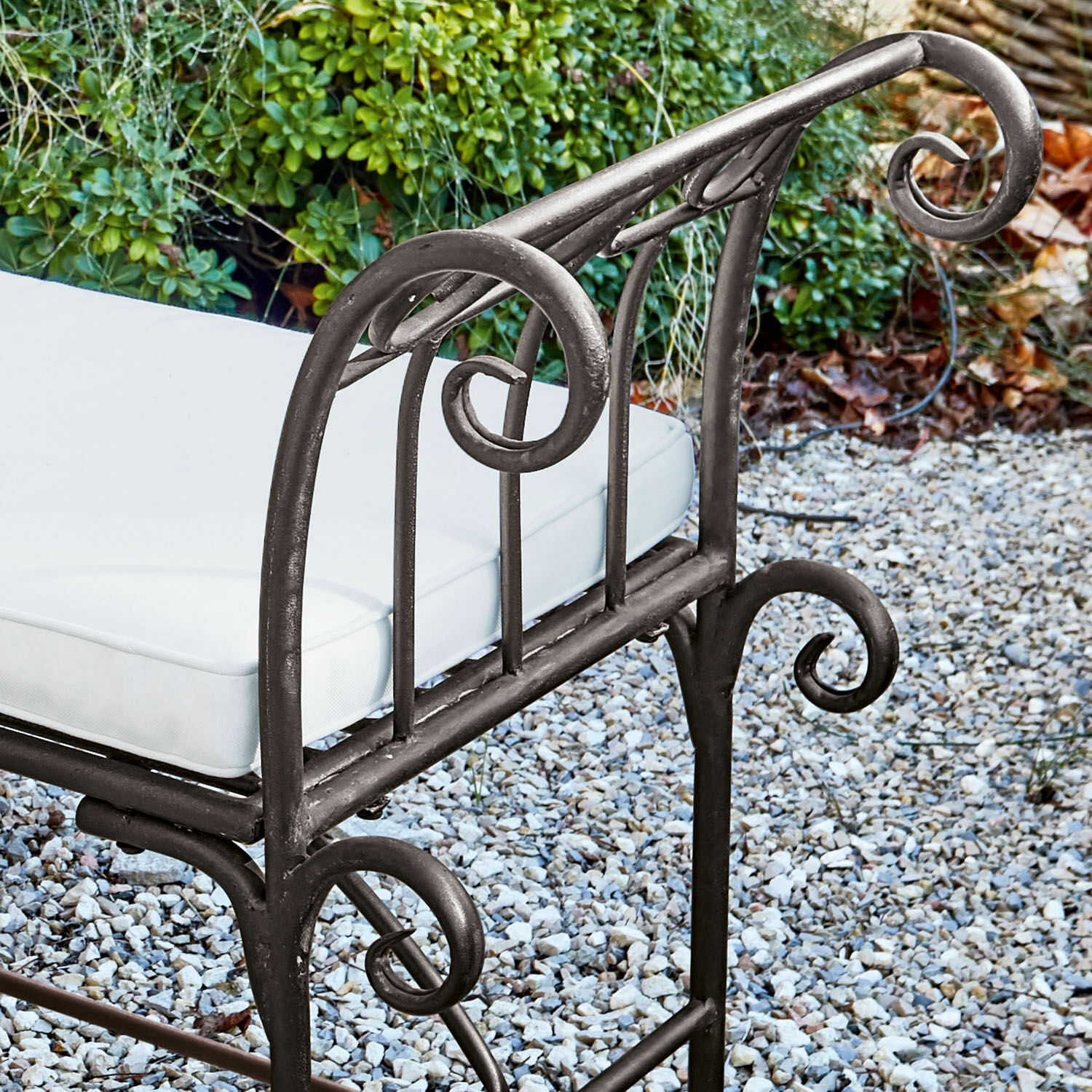 Metall-Gartenstuhl mit weißem Polster auf Kiesboden, dekorativer Metallstuhl für Terrasse