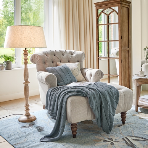 Beiger Chesterfield-Sessel mit Holzbeinen und blauem Strickplaid in hellem Wohnzimmer