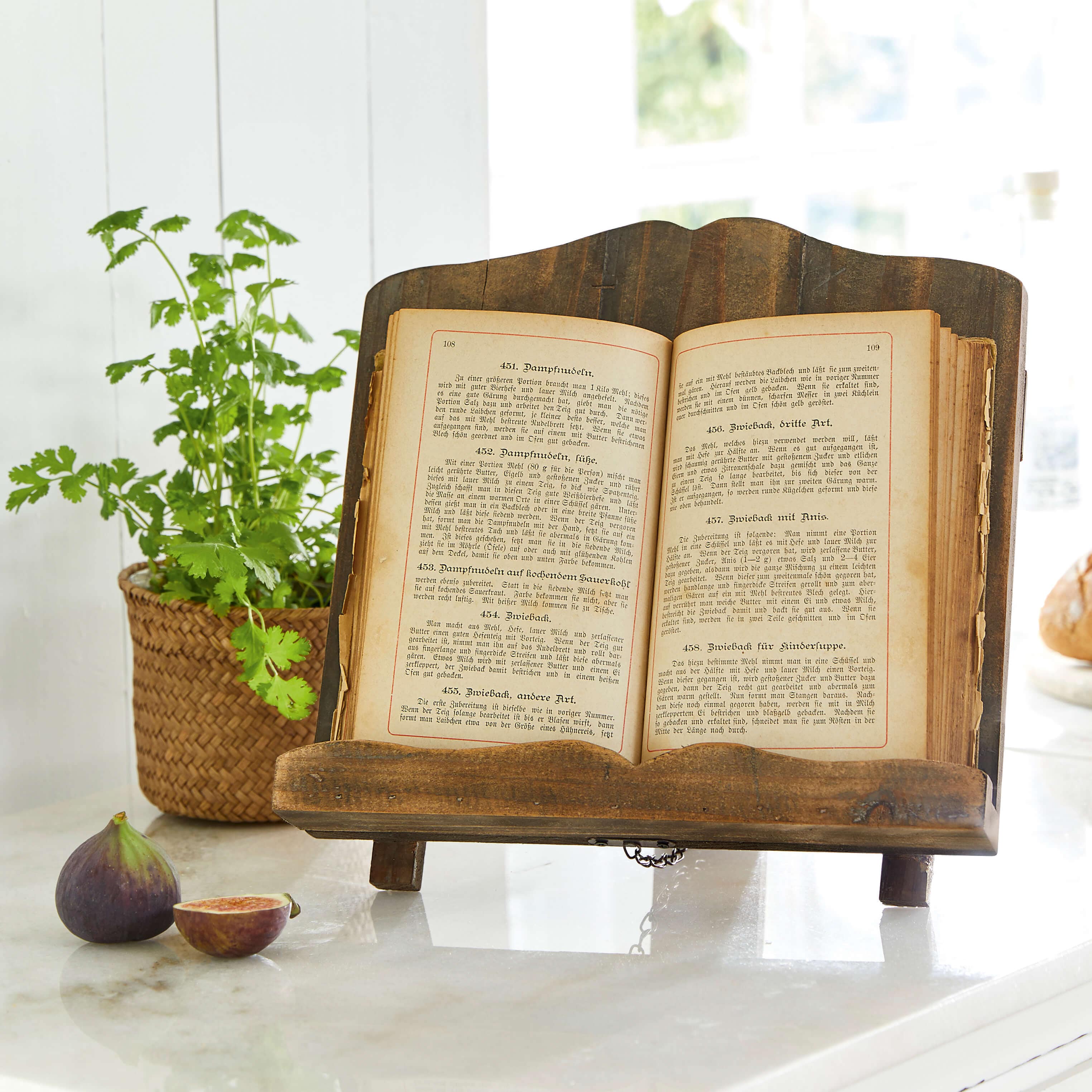 Dunkler Holzbuchständer mit offenem altem Kochbuch auf Marmorarbeitsplatte