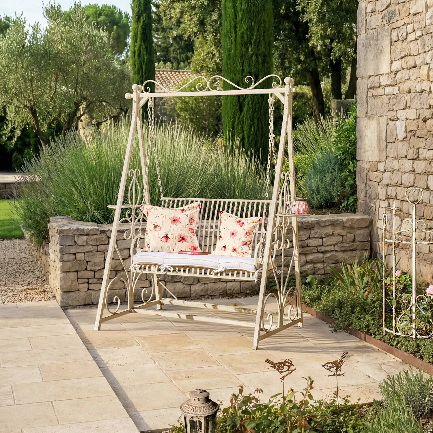 Metall-Gartenschaukel in Creme mit floral gemusterten Kissen auf Naturstein-Terrasse