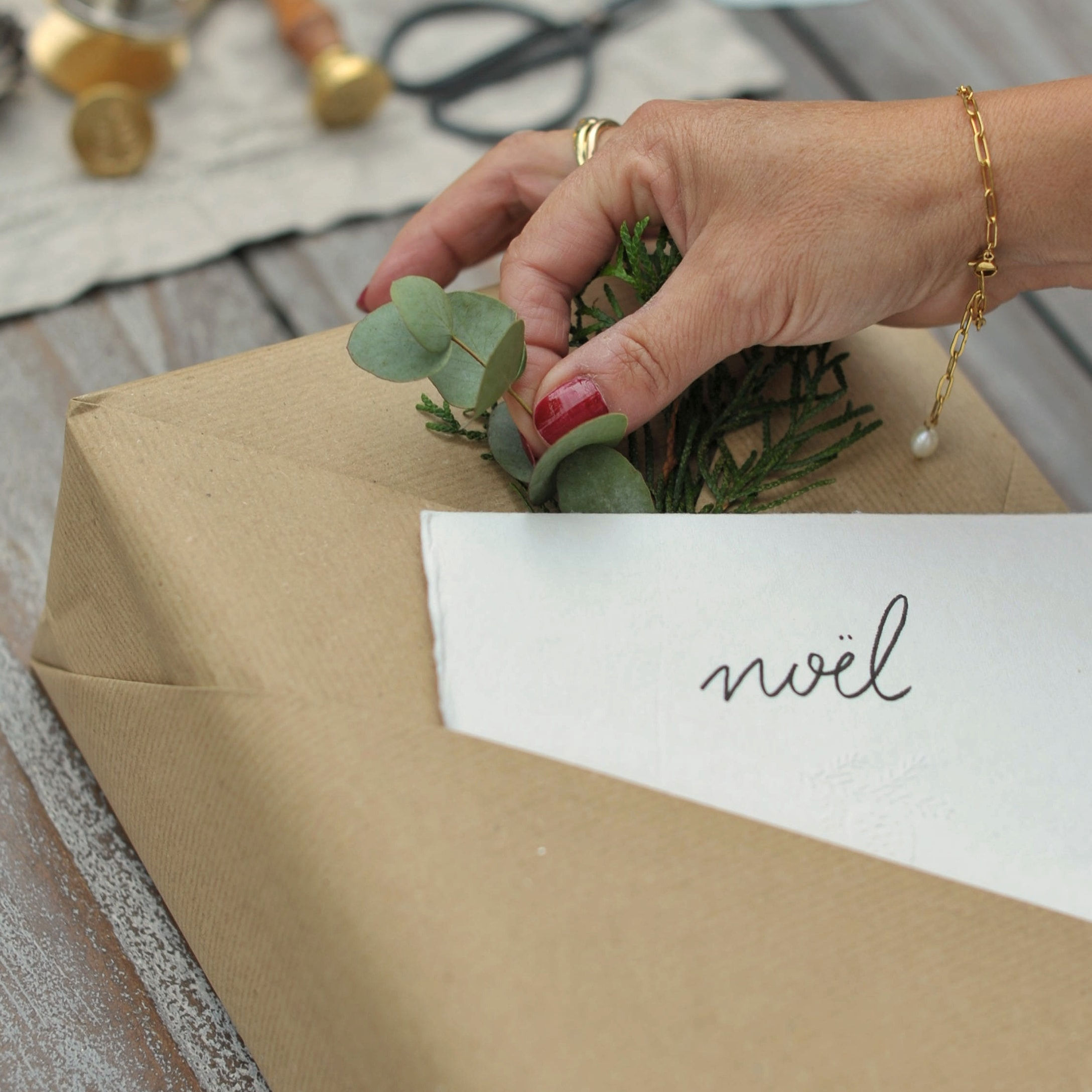 Hand dekoriert Geschenk in braunem Papier mit grünen Blättern und Karte mit Schriftzug noël