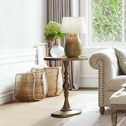 Runder Beistelltisch aus braunem Metall mit Lampe und Dekoration in hellem Wohnzimmer