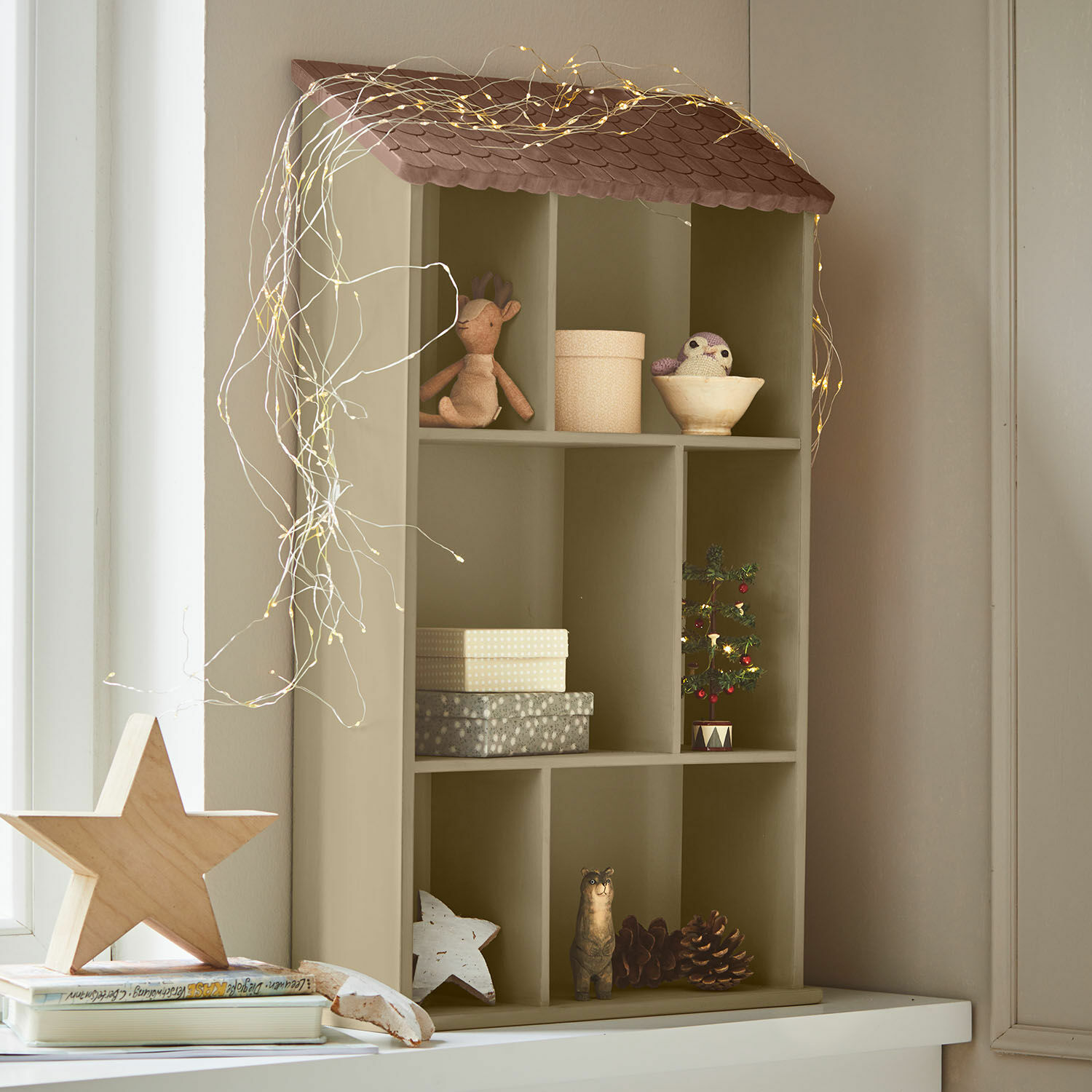 Wandregal Zerith Olivefarbenes Holzregal in Hausform mit Weihnachtsdekoration und LED-Lichterkette für heimelige Stimmung