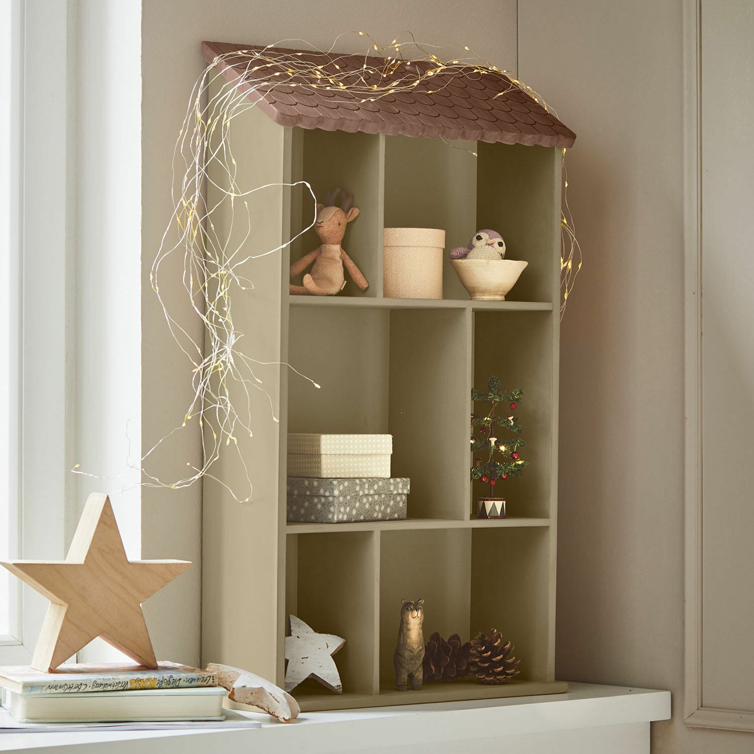 Wandregal Zerith Olivefarbenes Holzregal in Hausform mit Weihnachtsdekoration und LED-Lichterkette für heimelige Stimmung