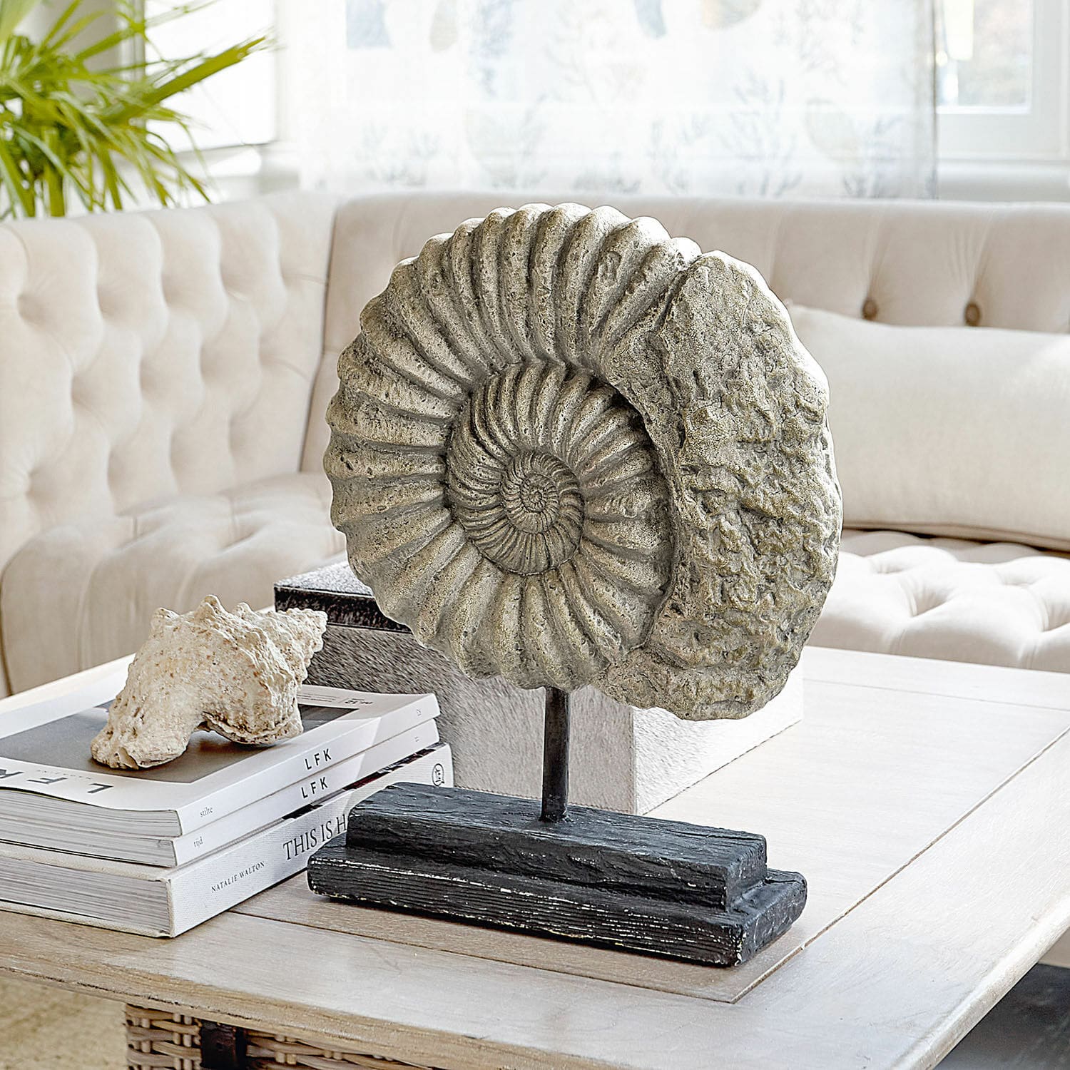 Deko-Objekt Dewey Dekorative Ammoniten-Skulptur aus Stein auf schwarzem Sockel auf einem Couchtisch im Wohnzimmer