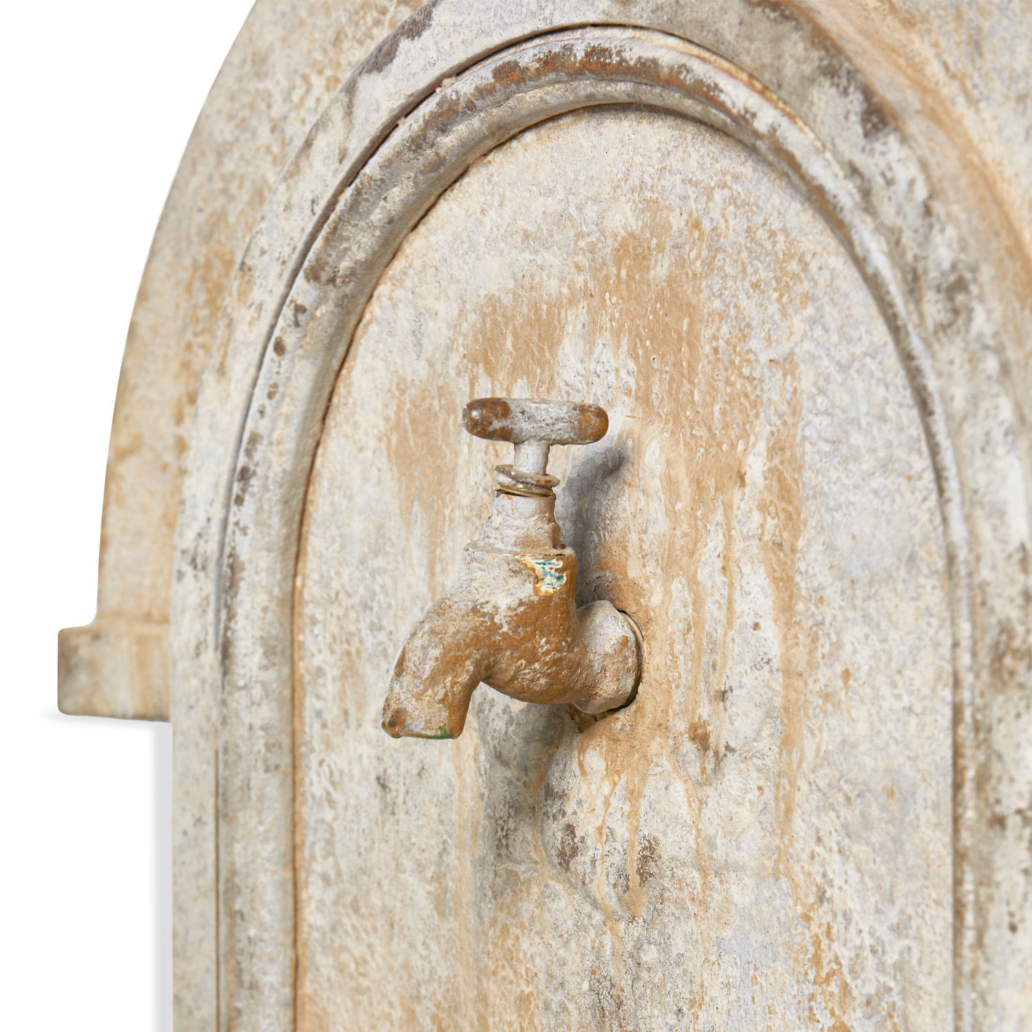 Alter Metall-Wasserhahn mit Rost auf beiger, verwitterter Steinwand als Gartendekoration