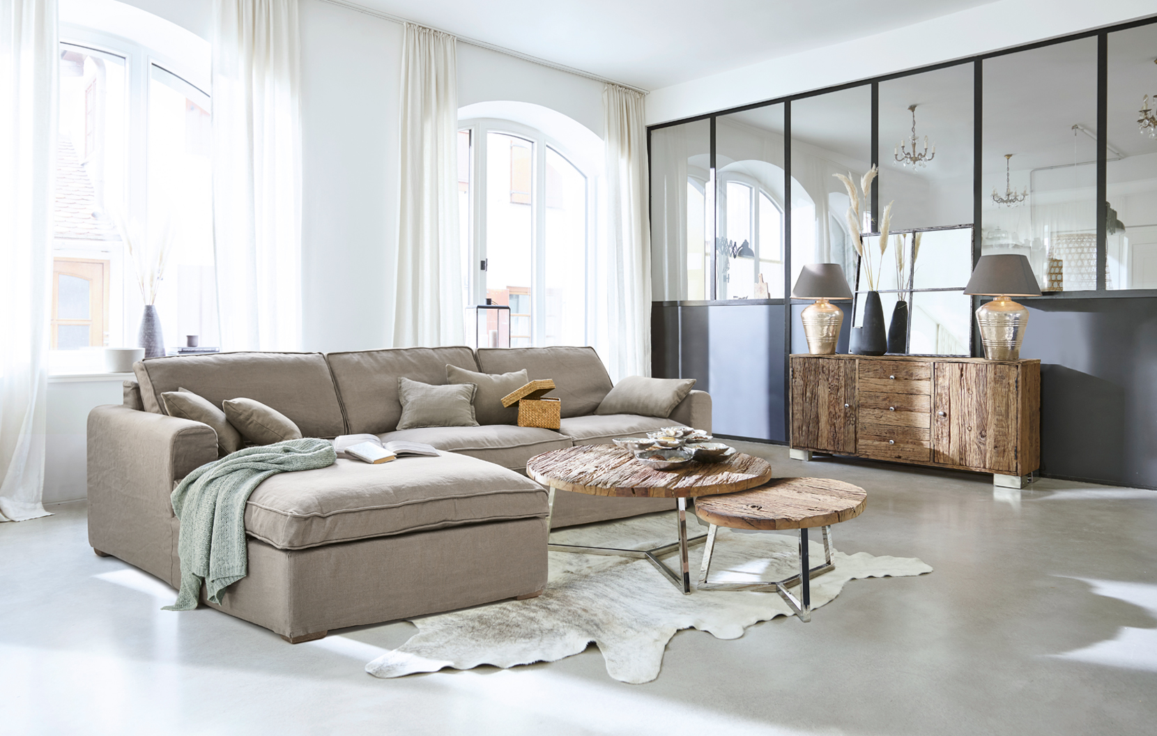 Helles Wohnzimmer mit beigem Stoffsofa und rustikalen Holztischen im modernen Industriestil