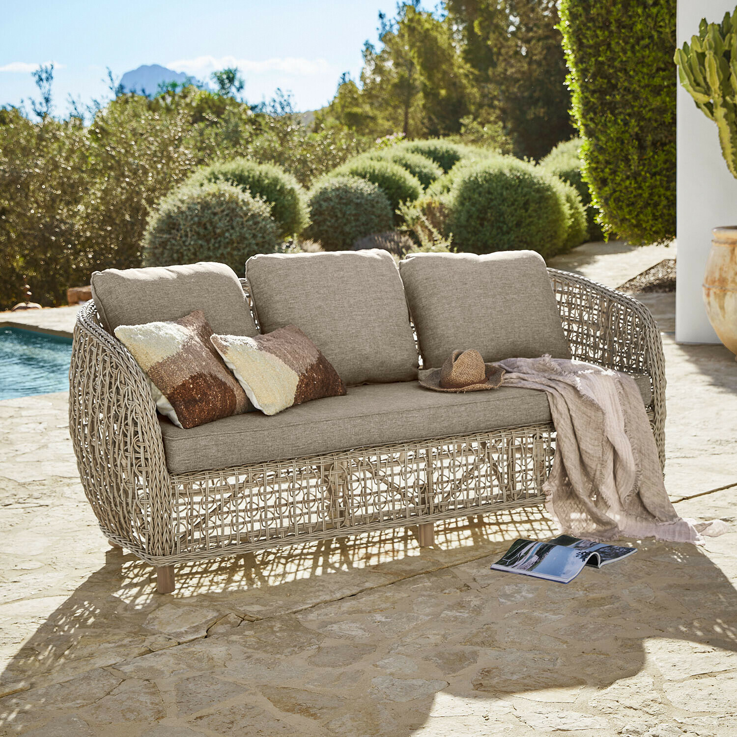 Sofa Ventiglio Gartensofa mit beigen Polstern und geflochtenem Rattangestell auf steinerner Terrasse am Pool