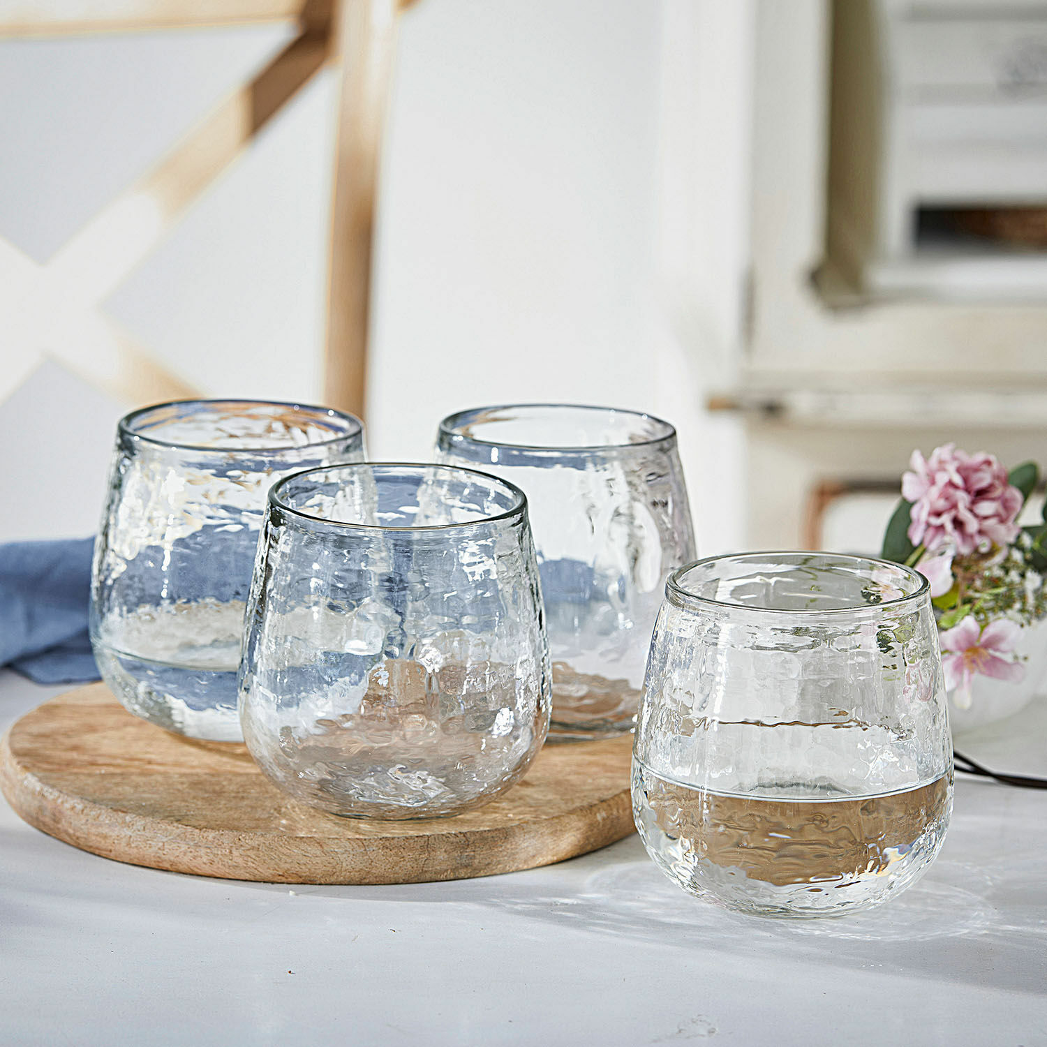 Set aus vier transparenten Gläsern aus strukturiertem Glas auf Holzbrett für Getränke