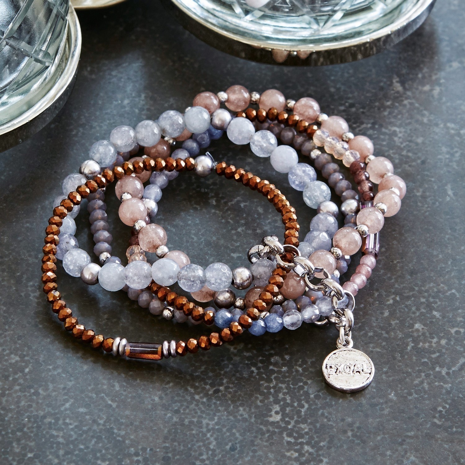Set aus Armbändern mit braunen und grauen Stein- und Metallperlen auf dunklem Untergrund