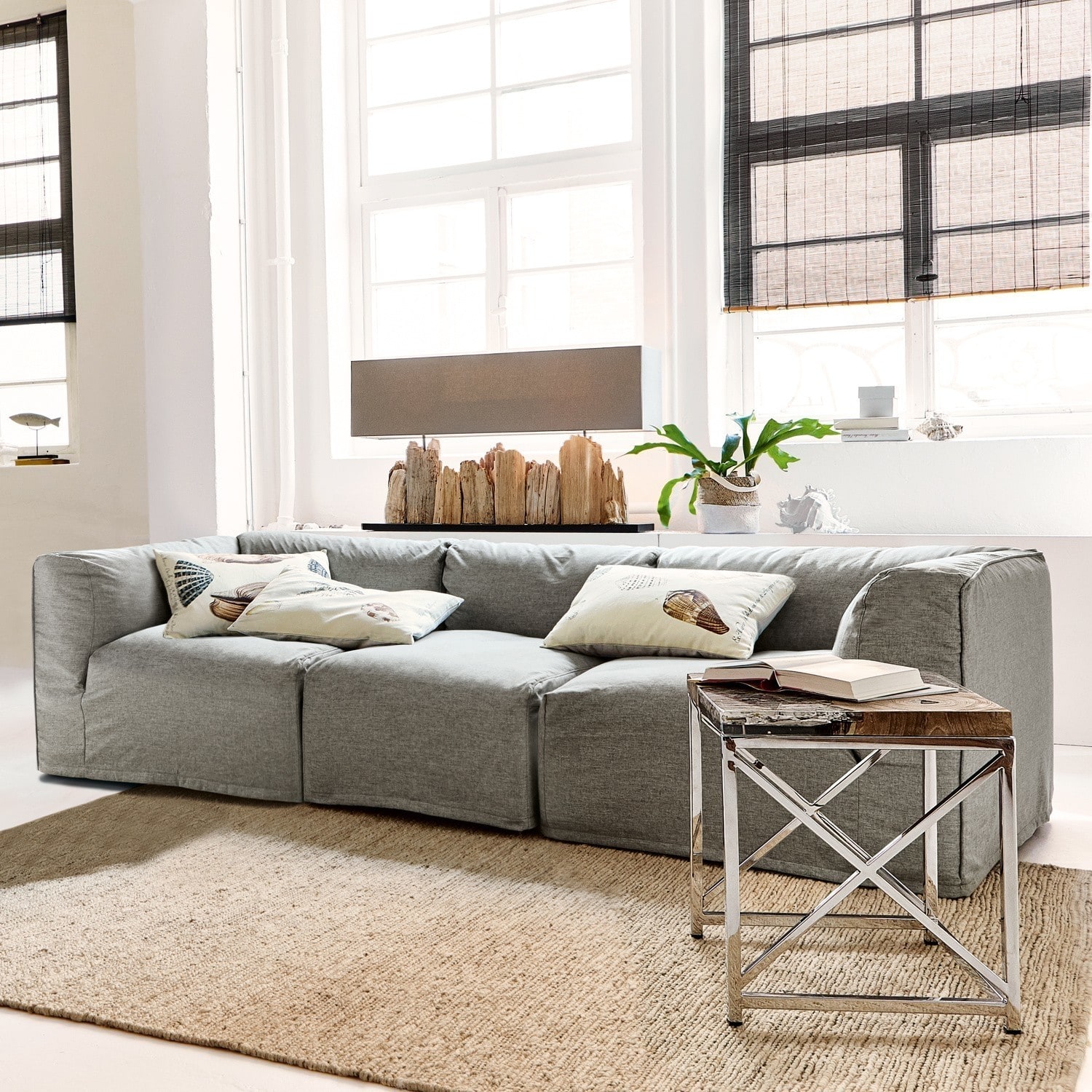 Graues Stoffsofa in modernem Wohnzimmer mit dekorativen Kissen und Beistelltisch aus Holz und Metall