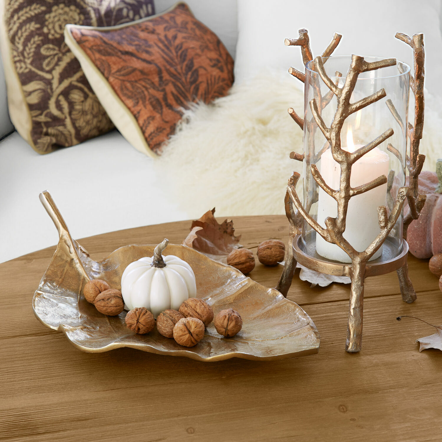 Goldene Blattformige Schale mit weißem Kürbis und Walnüssen auf Holztisch als Herbstdeko