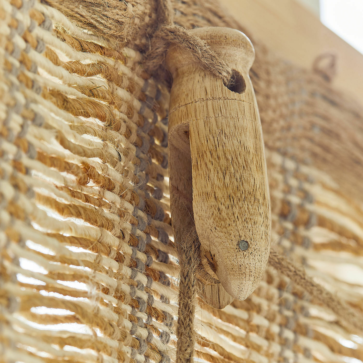 Holzgriff mit Naturseil vor beige-braun gewebtem Stoff in warmen Farbtönen