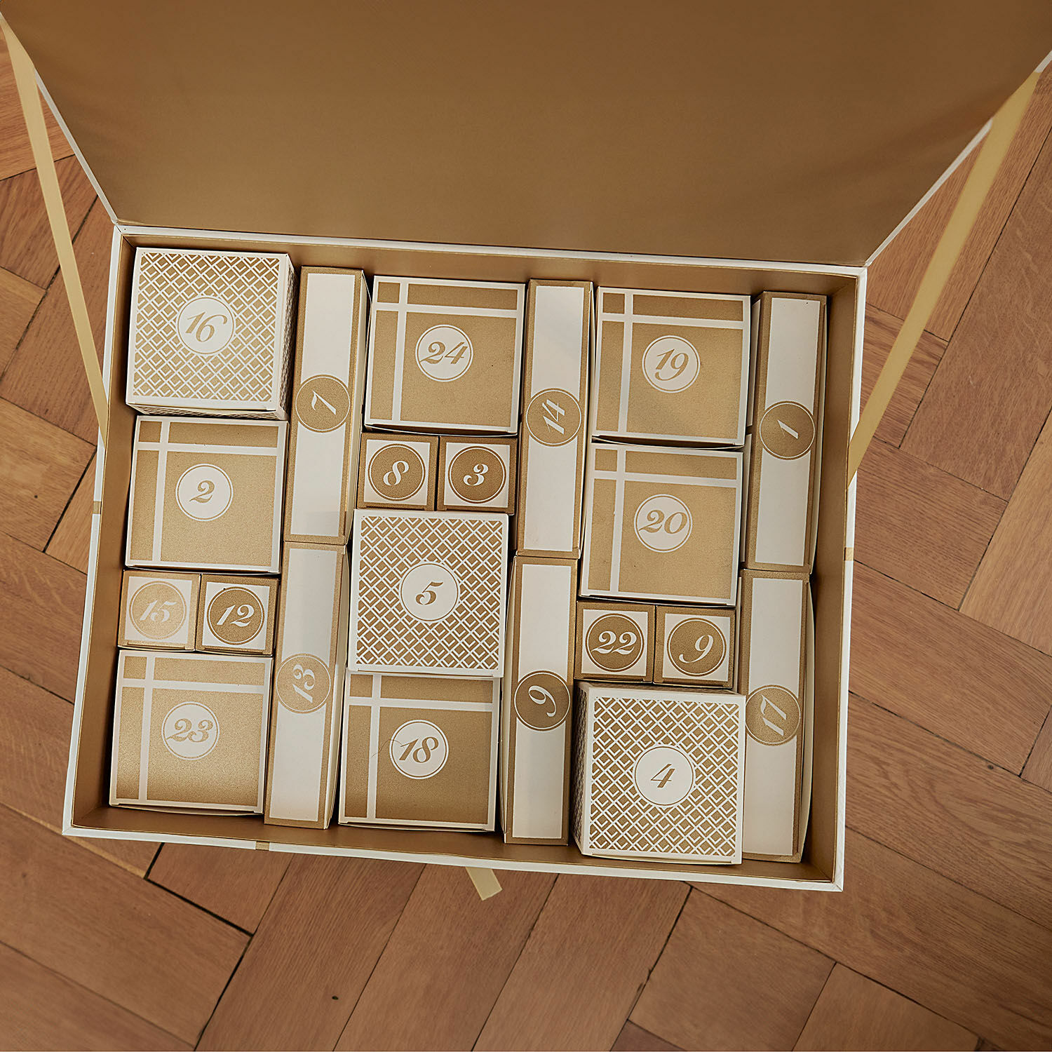 Set aus 24 gold-weißen Adventskalender-Schachteln auf Holzparkettboden