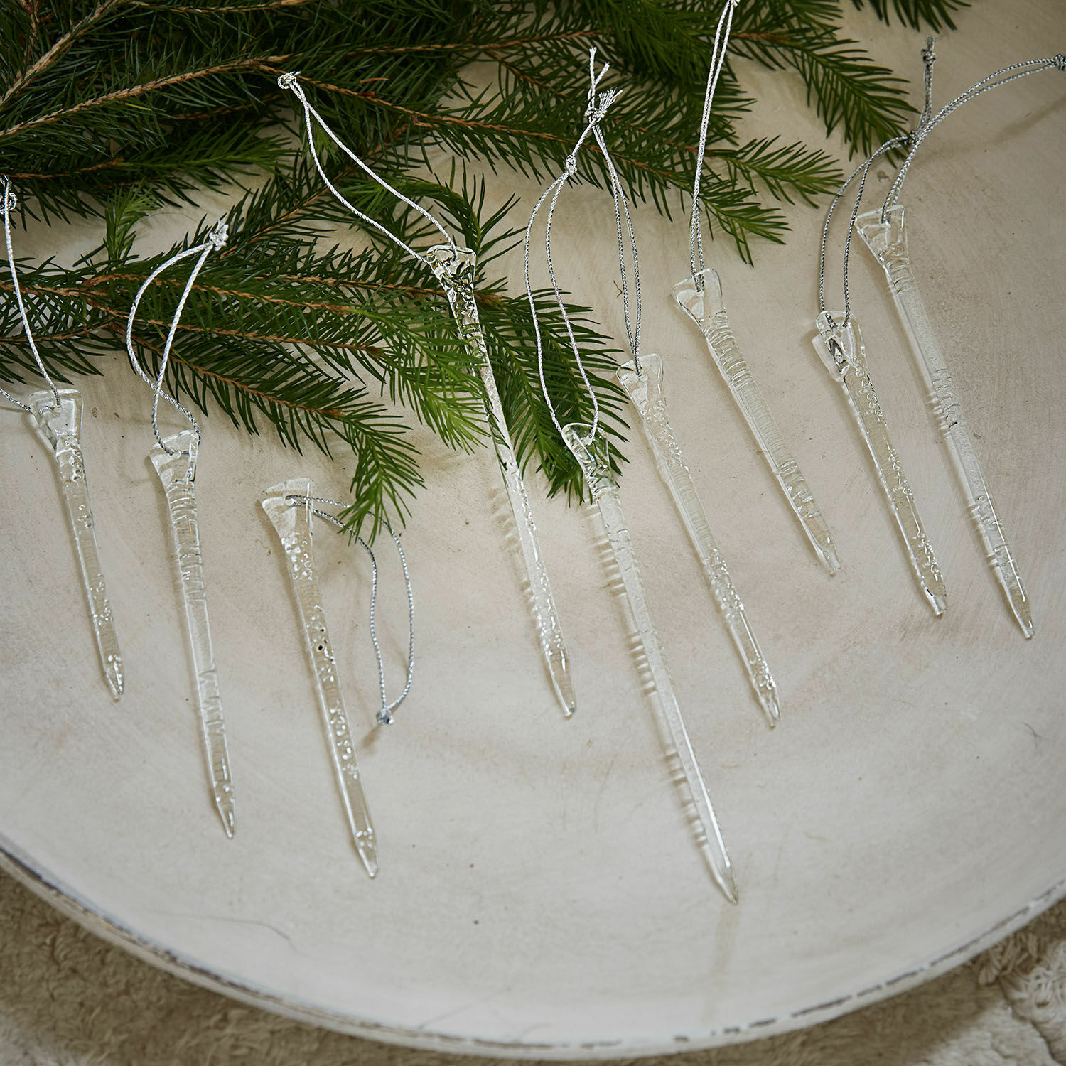 Transparente Weihnachtsanhänger in Eiszapfenform mit Aufhängeschlaufen auf Tannenzweigen
