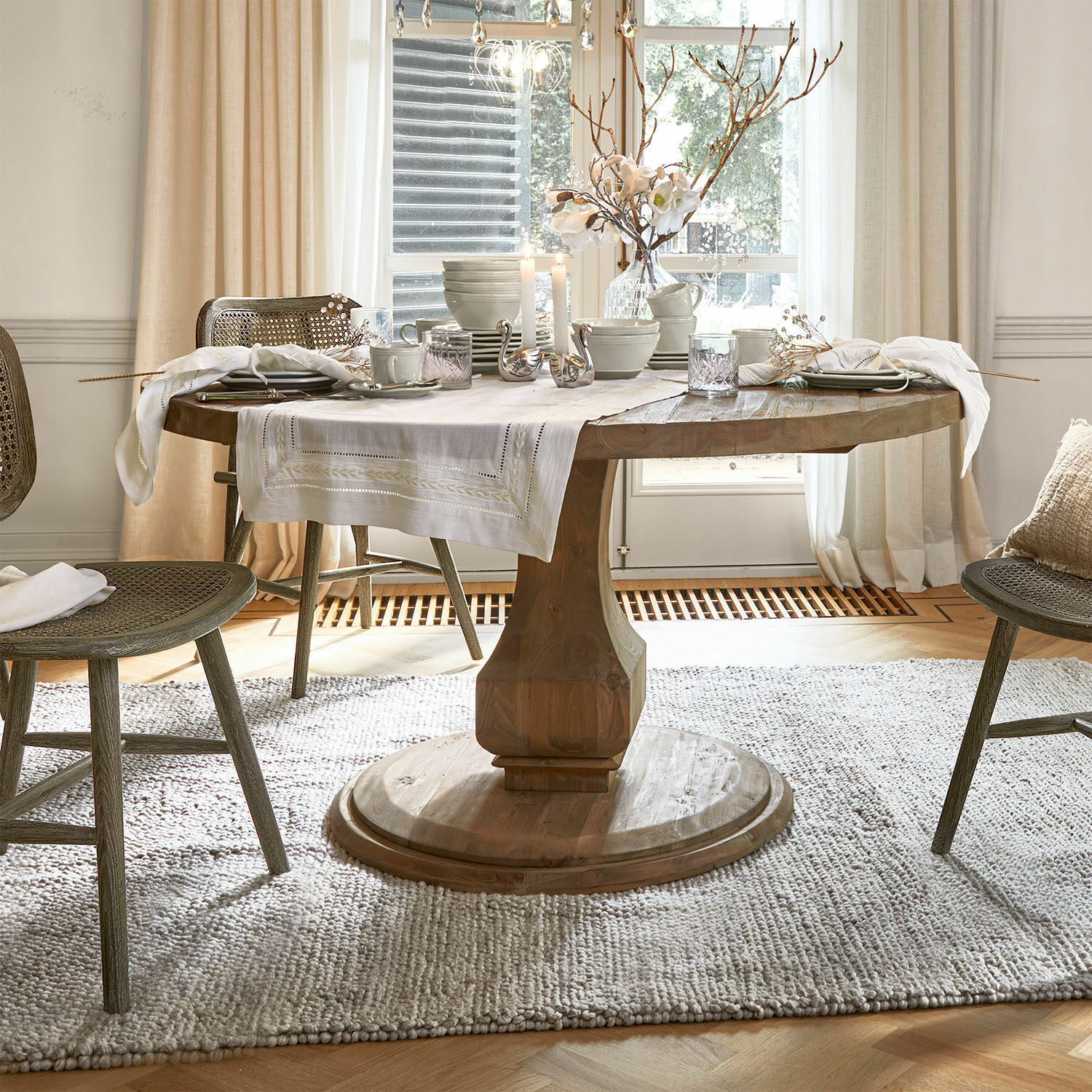 Tisch Alderwick Runder Holztisch mit weißem Tischläufer und Dekoration in hellem, gemütlichem Esszimmer mit Tageslicht