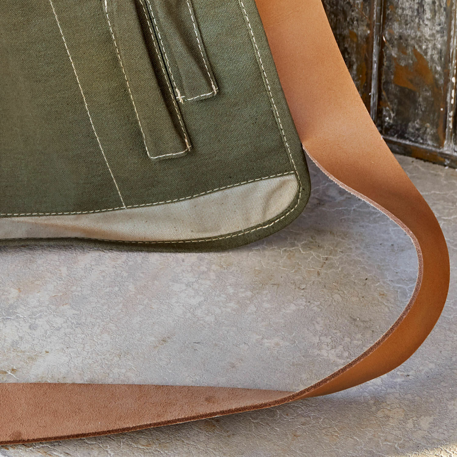 Grüne Stofftasche mit hellbeigem Abschluss und braunem Lederriemen