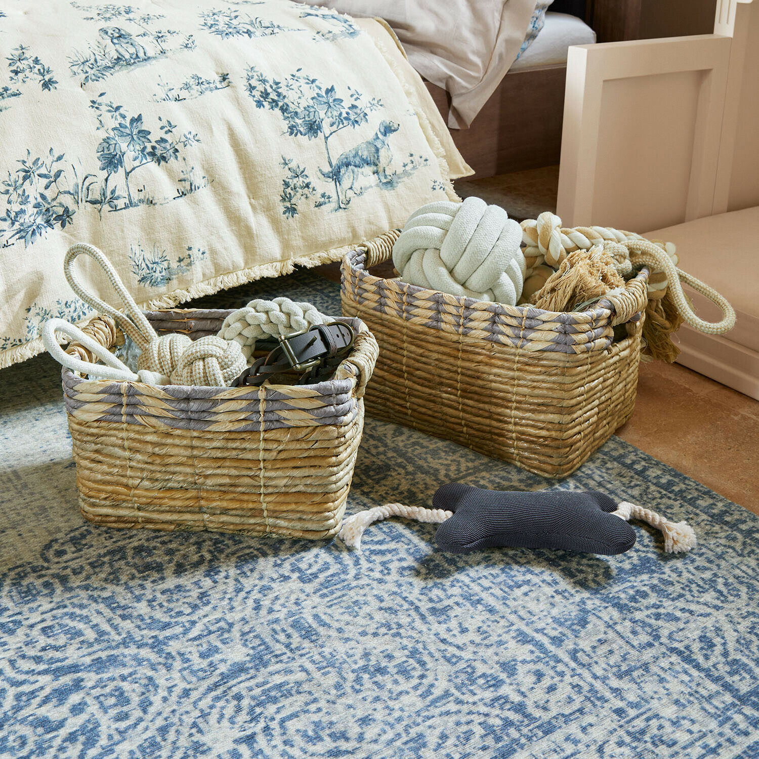 Zwei natürliche Korbwarenkörbe mit Hundespielzeug auf blauem Teppich im Schlafzimmer
