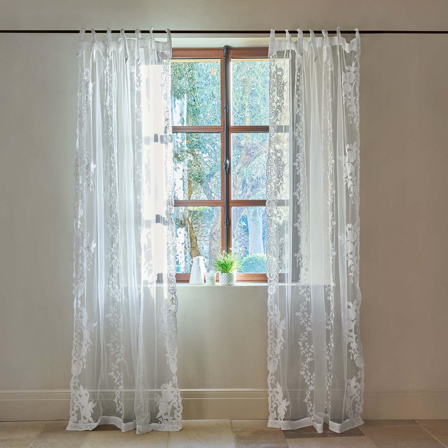 Transparente weiße Gardinen mit besticktem Blumenmuster an Holzfenster