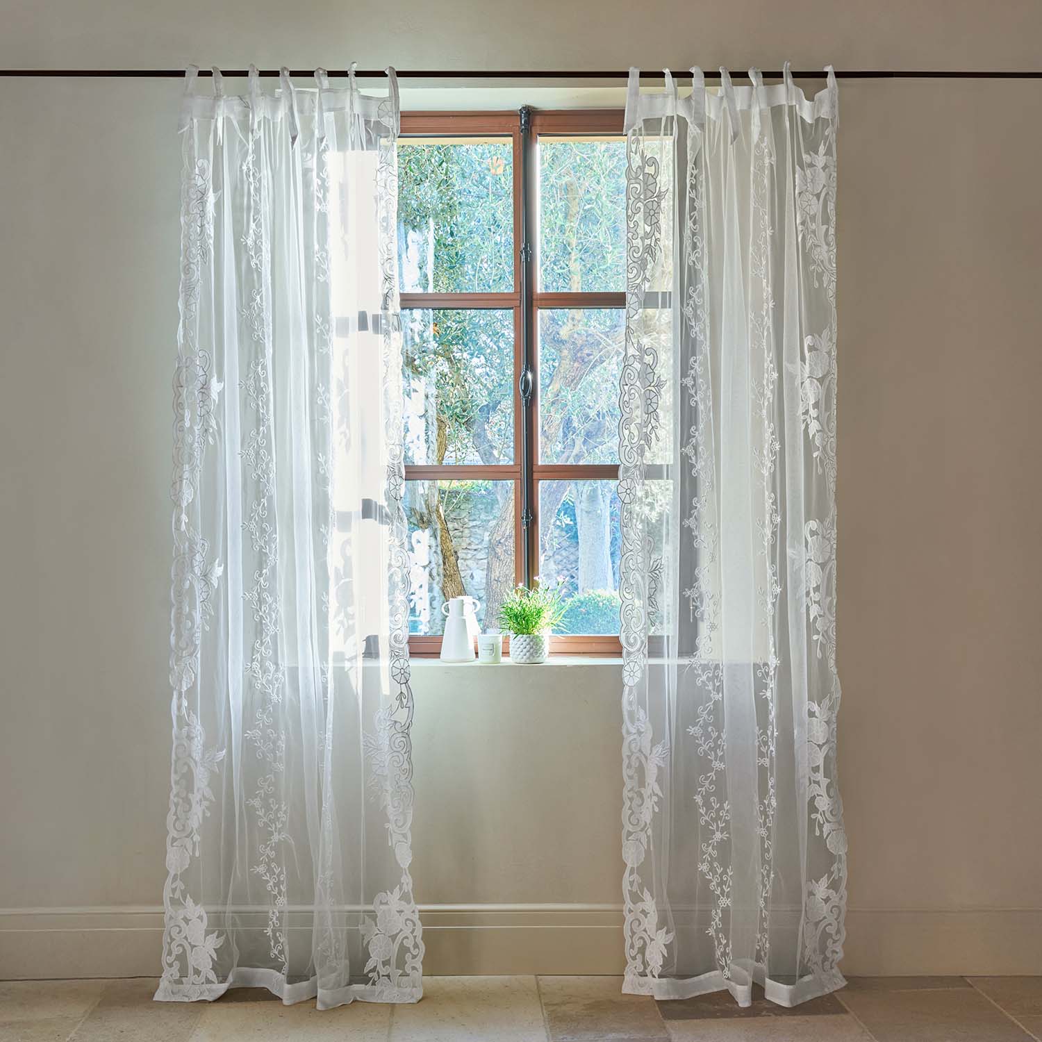 Transparente weiße Gardinen mit besticktem Blumenmuster an Holzfenster