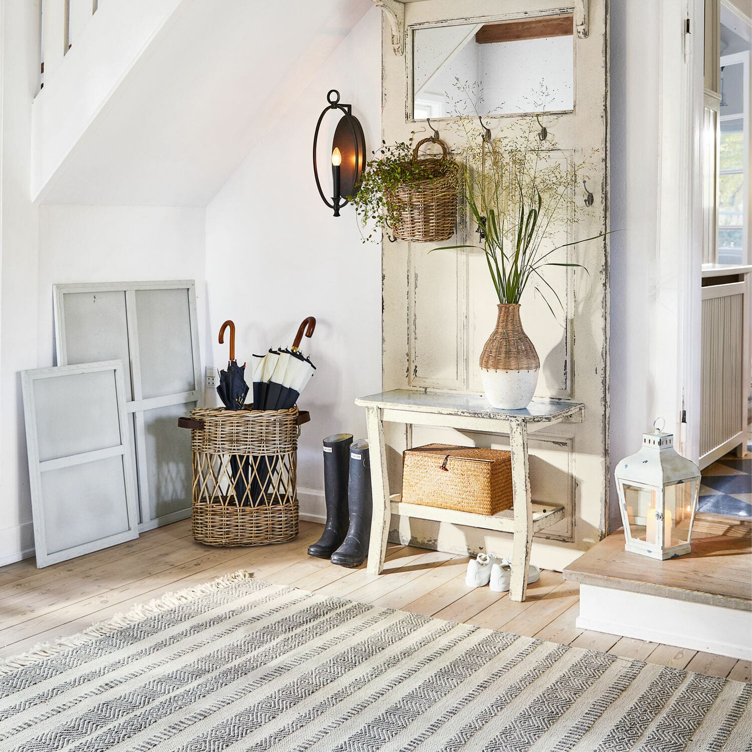 Gemütlicher Eingangsbereich mit weißer Holzbank, Korb aus Rattan und Vintage-Wandleuchte