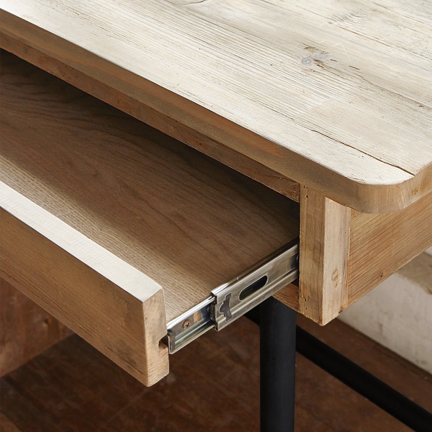 Tischplatte aus hellem Holz mit geöffneter Schublade und Metallführung auf schwarzem Bein