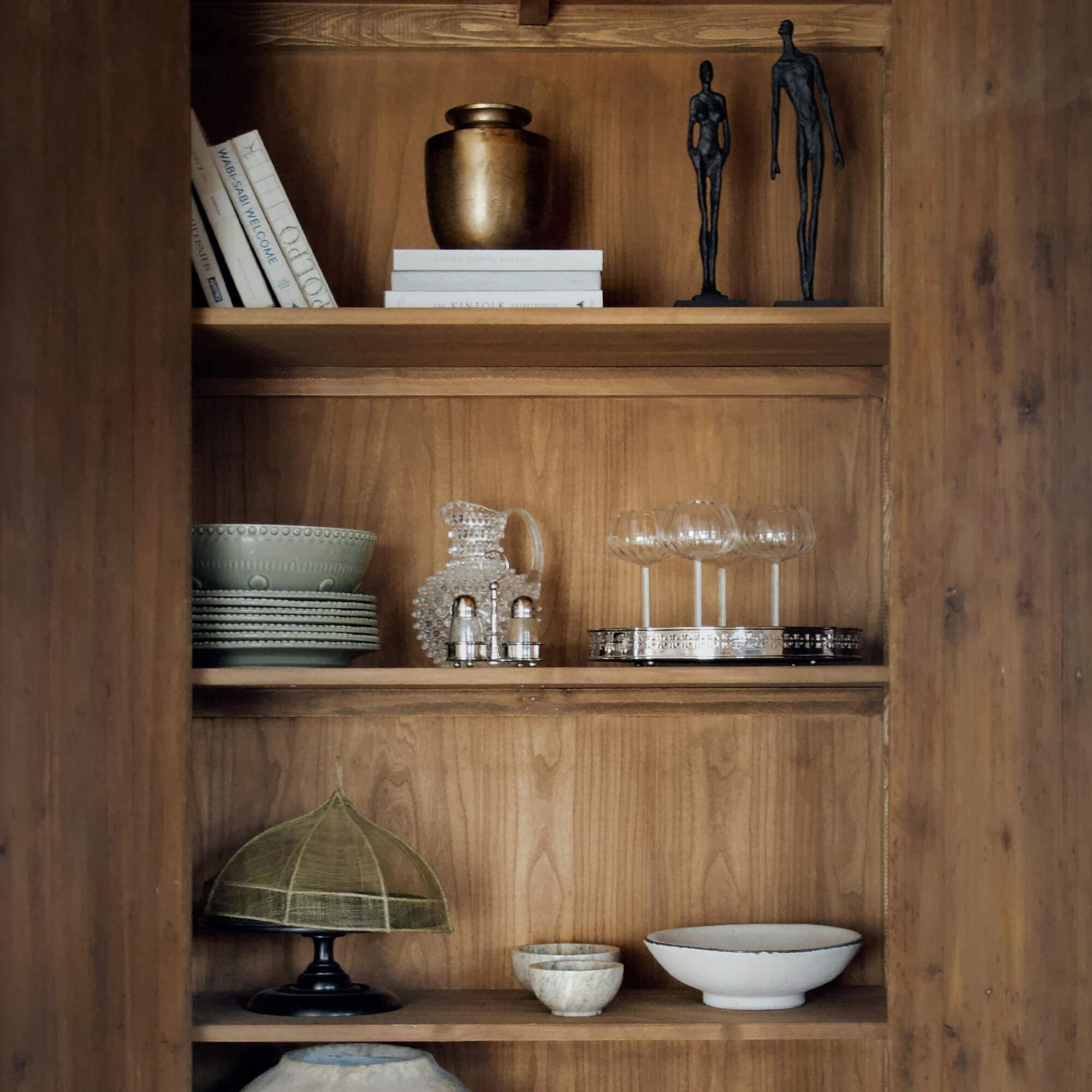 Holzregal mit dekorativen Objekten, Keramik und Weingläsern aus Glas