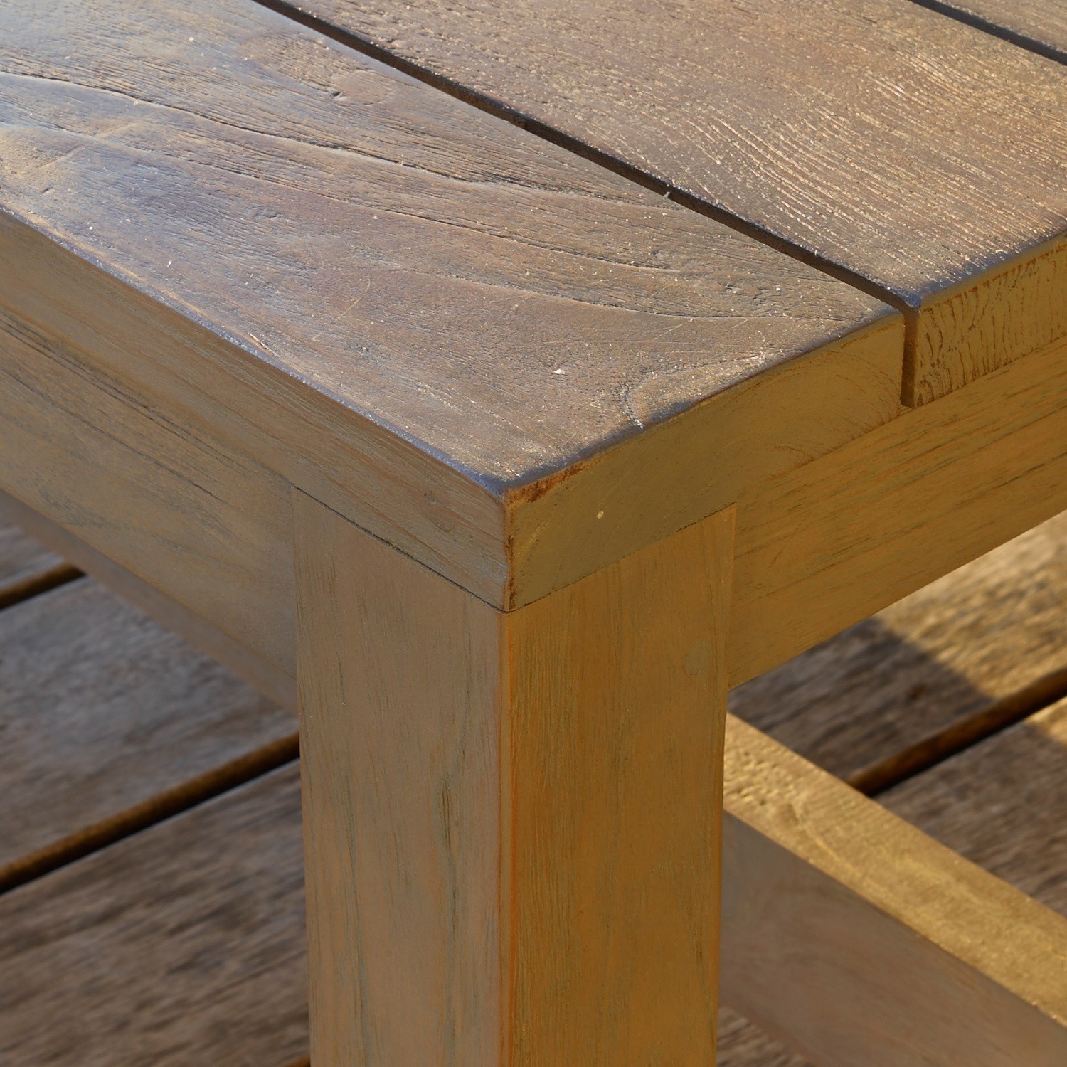 Eckdetail eines Gartentisches aus naturfarbenem Holz auf Holzterrasse
