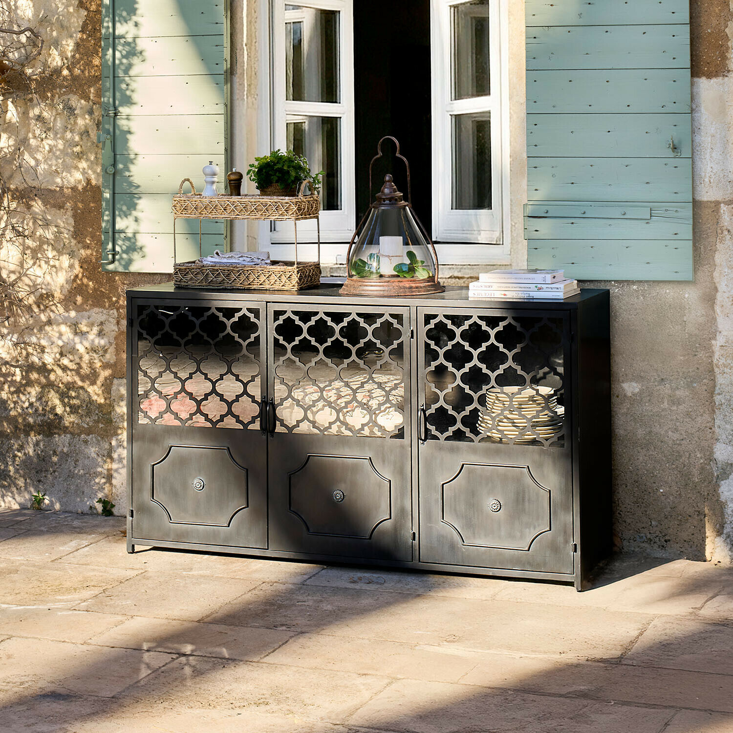 Sideboard Astralon Schwarzer Metall-Sideboard mit filigranen Türen auf Terrasse vor Fenster mit grünen Fensterläden
