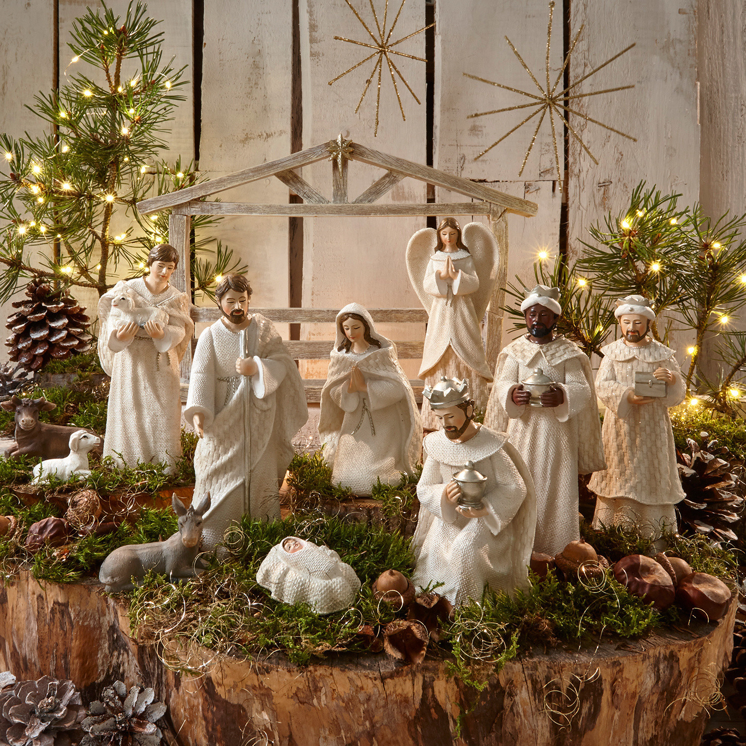 Krippenfiguren 12er Set Santo Weißes Krippenfiguren-Set aus Holz und Stoff auf natürlichem Moos- und Lichterhintergrund zur Weihnachtsdekoration