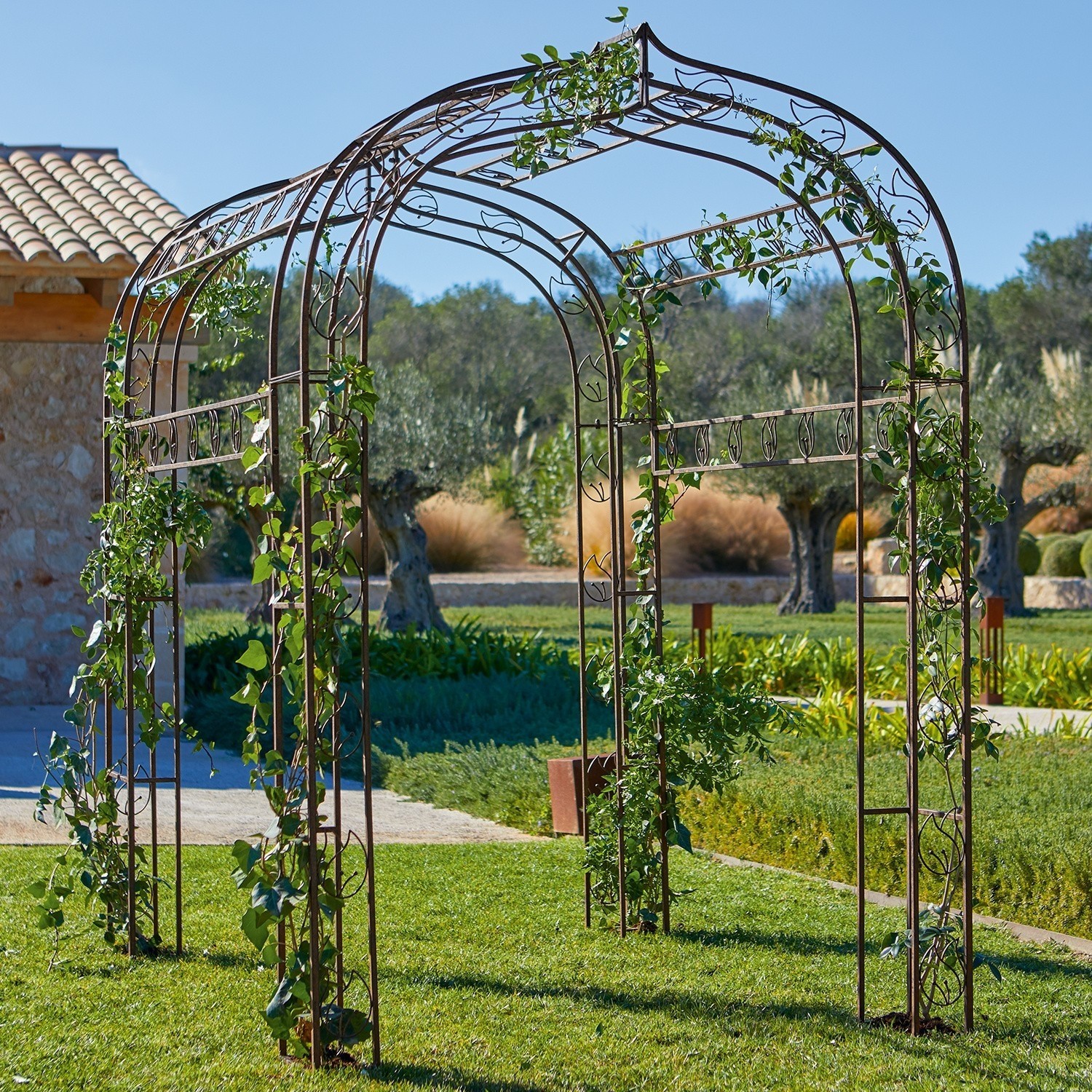 Metall-Gartenpergola mit dekorativen Blättern und Kletterpflanzen auf grünem Rasen, Gartendekor