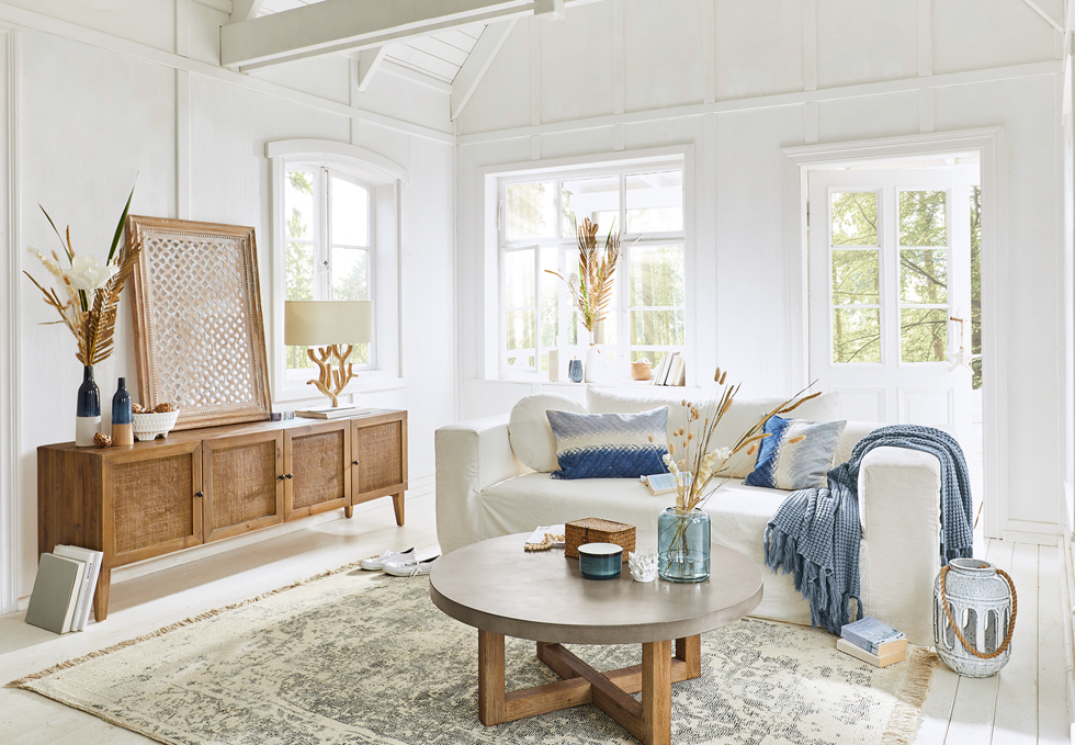 Helles Wohnzimmer im maritimen Stil mit weißem Sofa, Holzkommode und blauen Akzenten