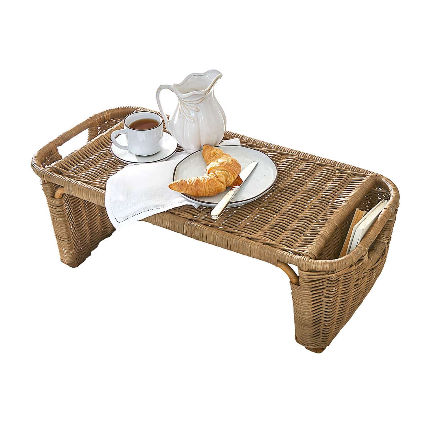 Brauner Rattantisch mit weißem Krug, Tasse und Croissant auf Teller für Frühstück