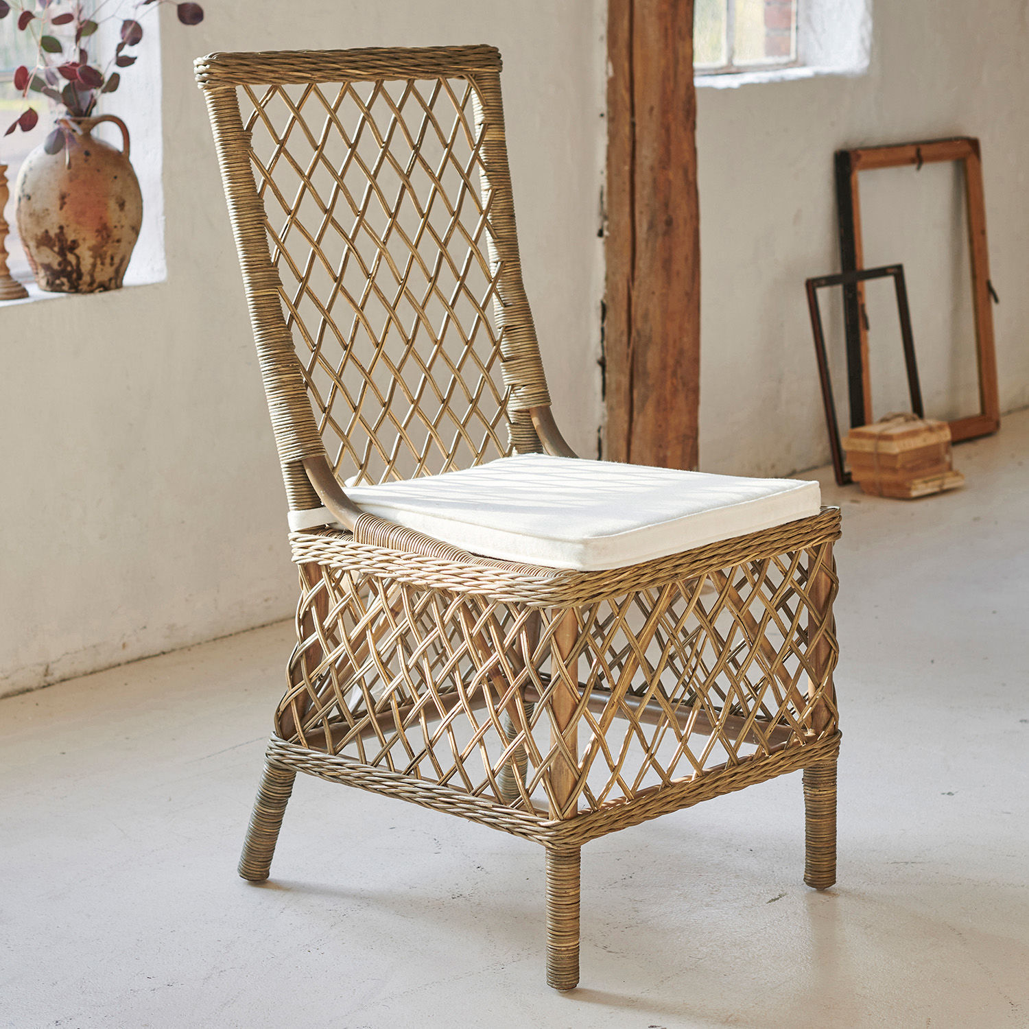 Rattanstuhl in Naturfarbe mit weißem Sitzkissen, ideal für Wohn- und Gartenbereiche