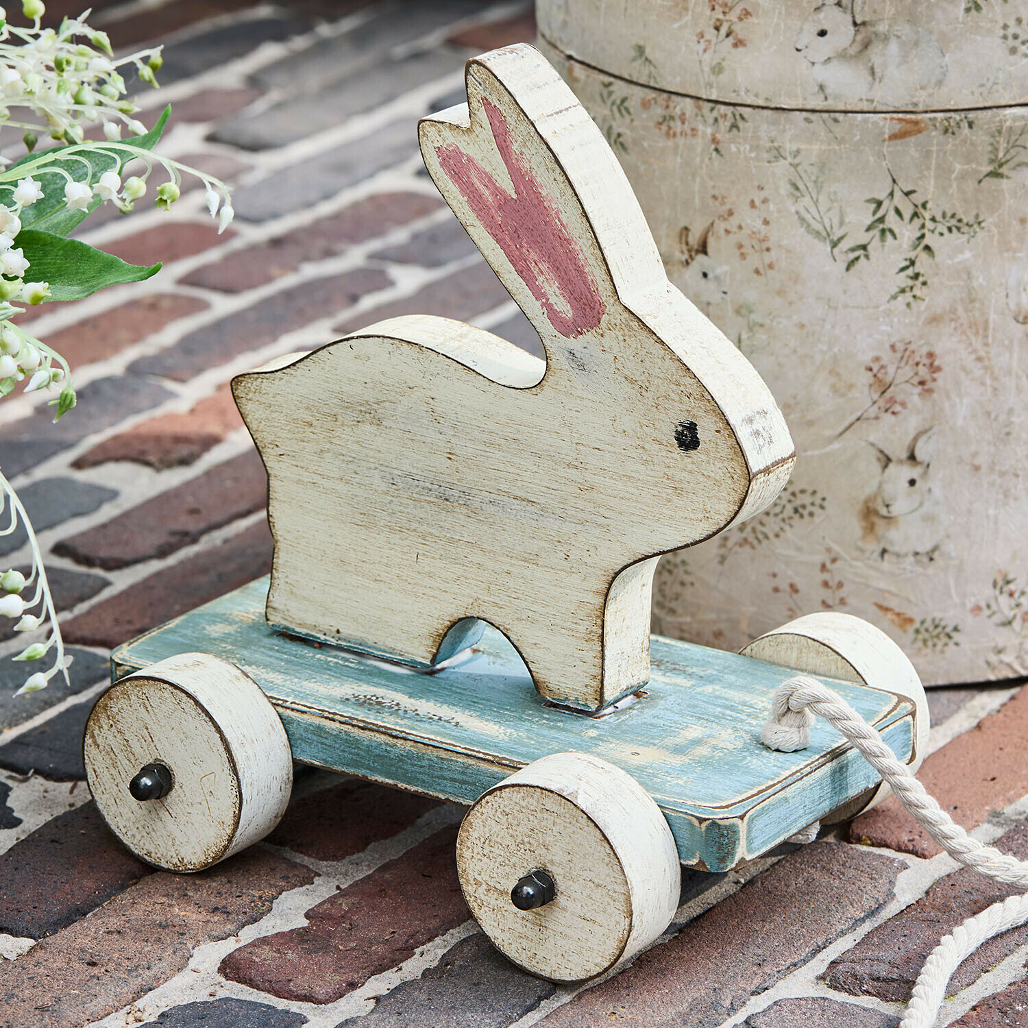 Ziehfigur Moiraine Holzspielzeug Hase in Weiß auf blauer Plattform mit Rädern und Zugseil, nostalgischer Stil